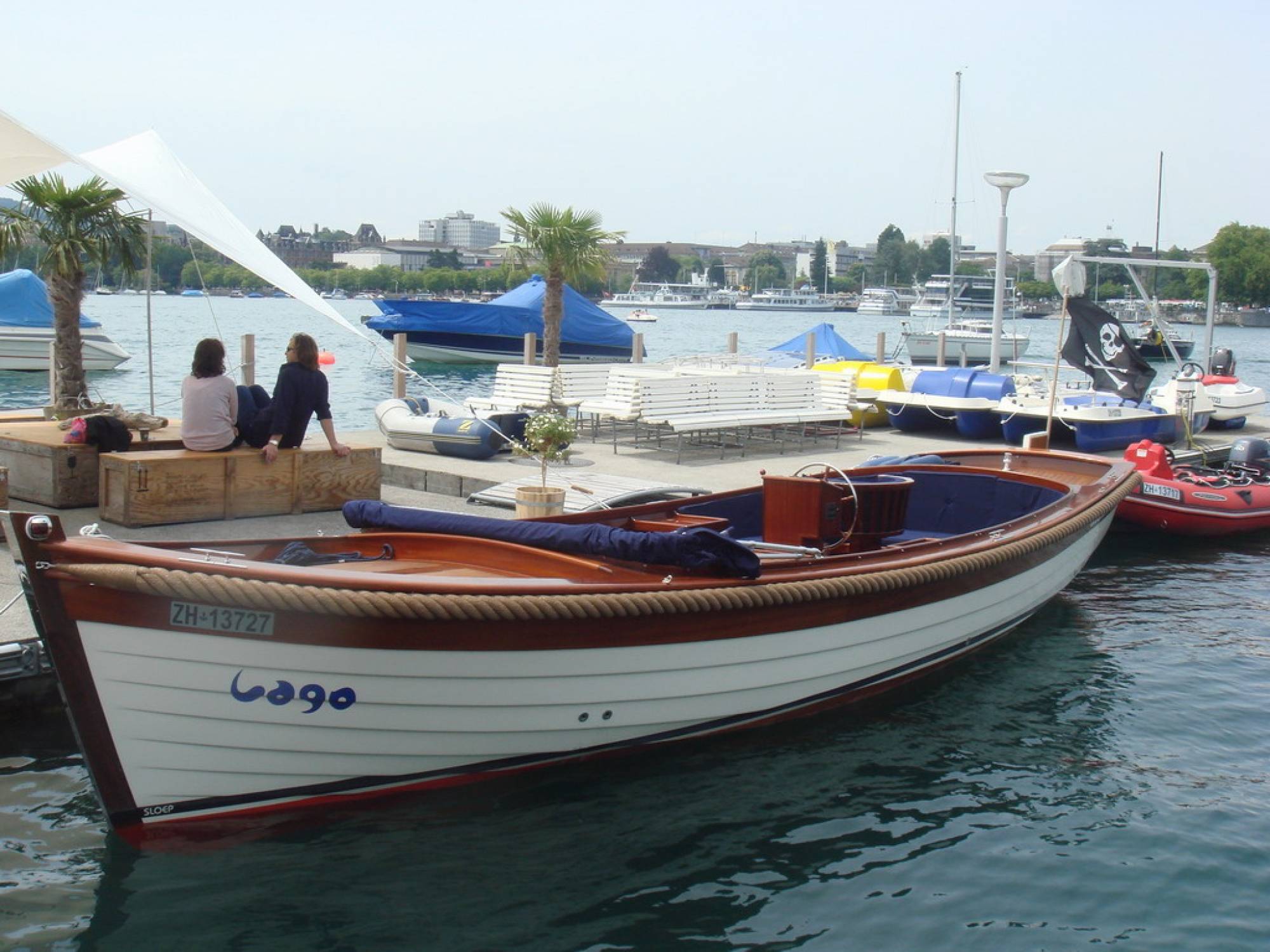 Plavba lodí po Zürichském jezeře, soukromá jachta s palmami a plachetnicemi na pozadí