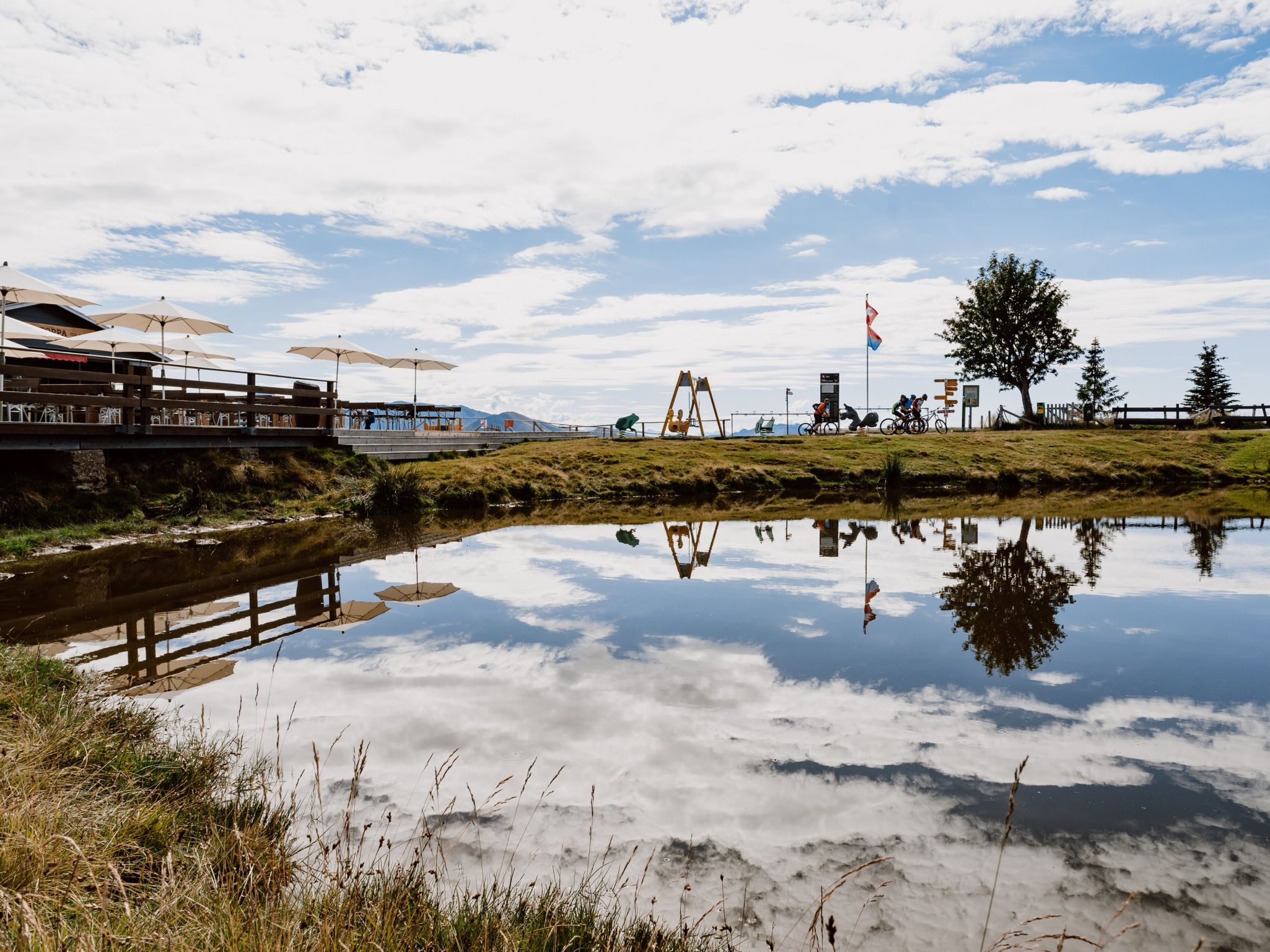 Monte Tamaro: lugn sjö med reflektion, omgiven av natur och fritidsaktiviteter.