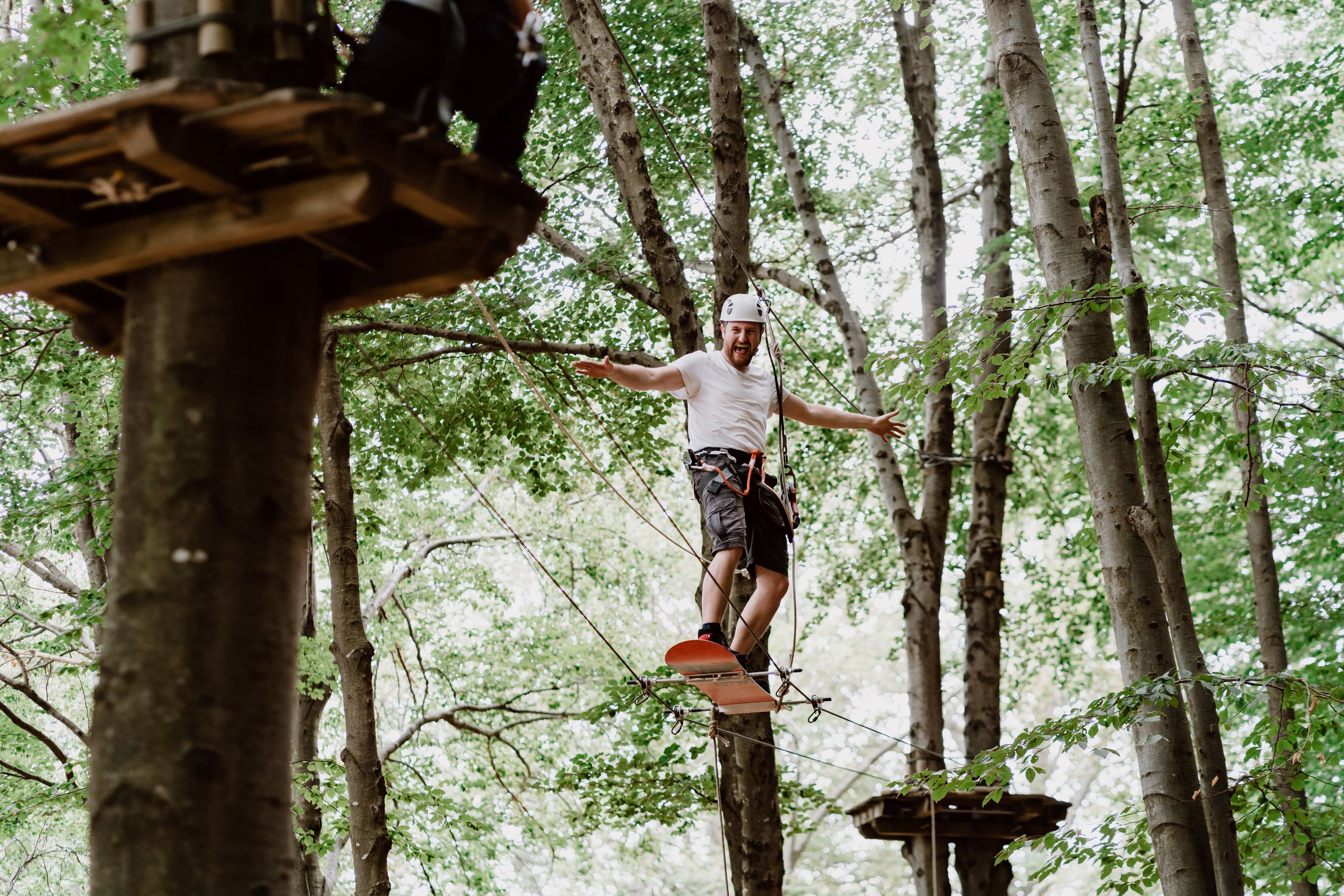 पेड़ के बीच हिलते हुए प्रतिभागी के साथ मंझधार में साहसी लोगों के लिए रास्ता मोंटे टामरो में