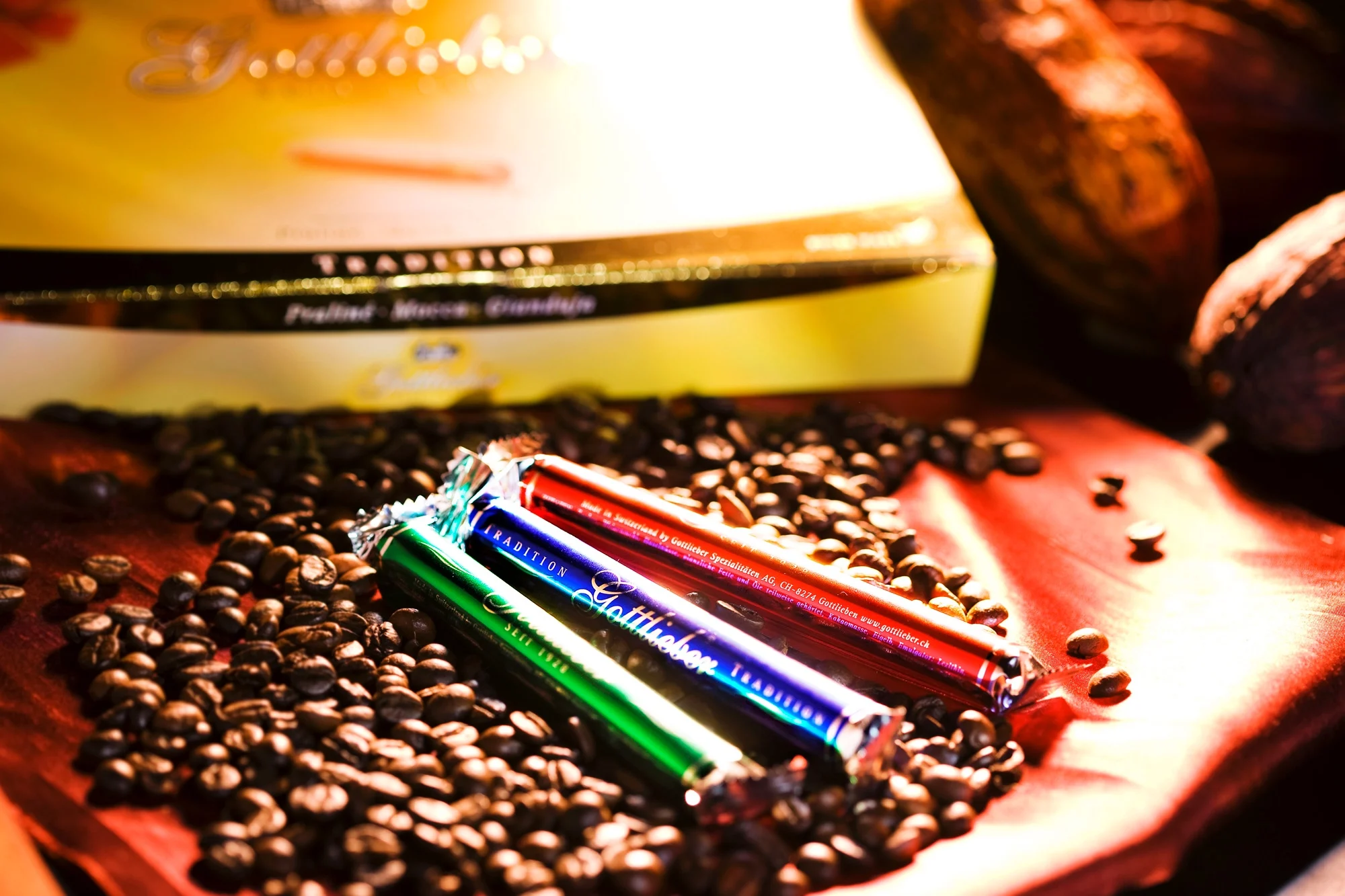 Gottlieber Hüppen s kávovými zrnky na červené látce. Čokoládové tyčinky v zeleném a červeném obalu.