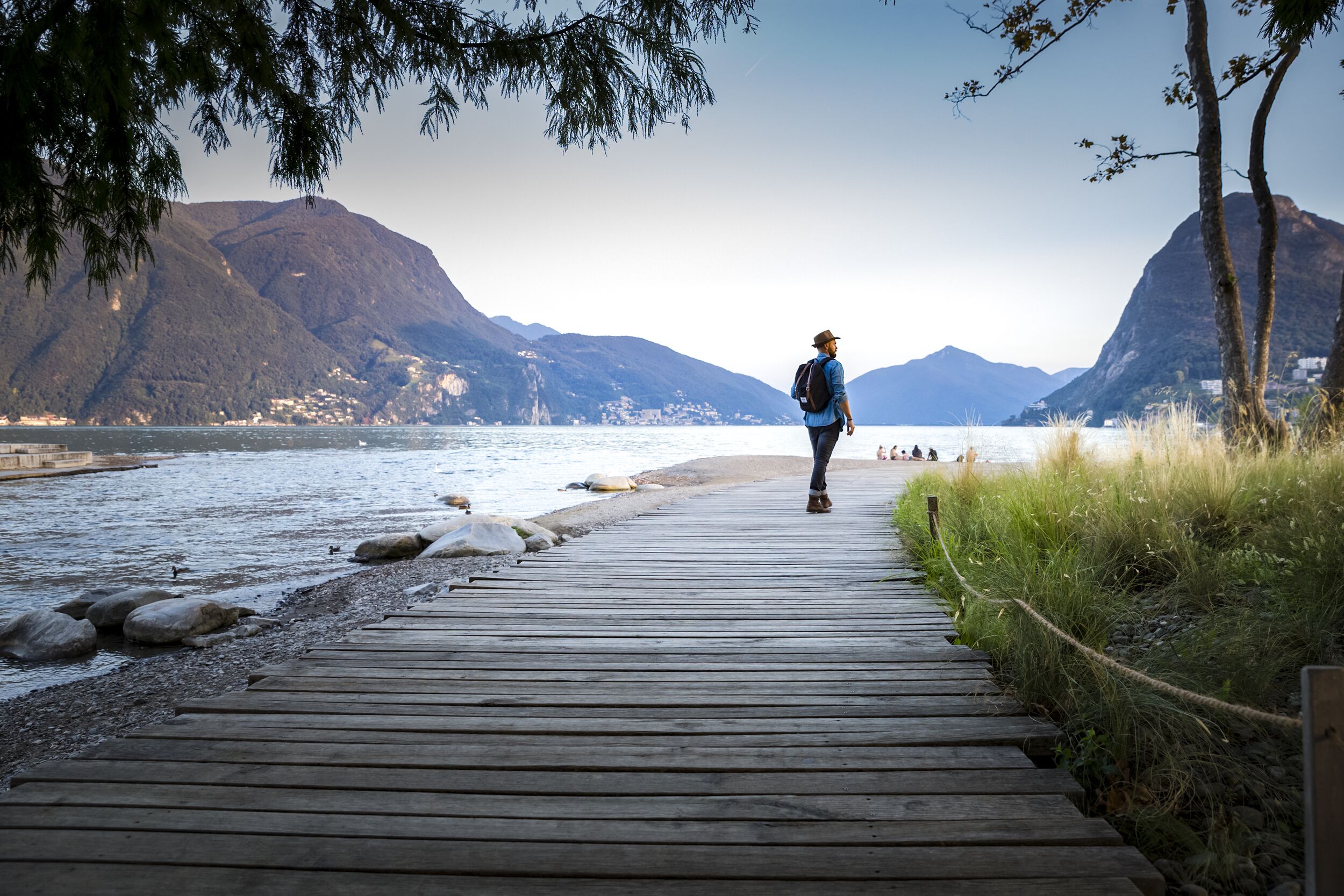 Passeggiata lungo il Lago di Lugano, ambiente tranquillo con montagne.