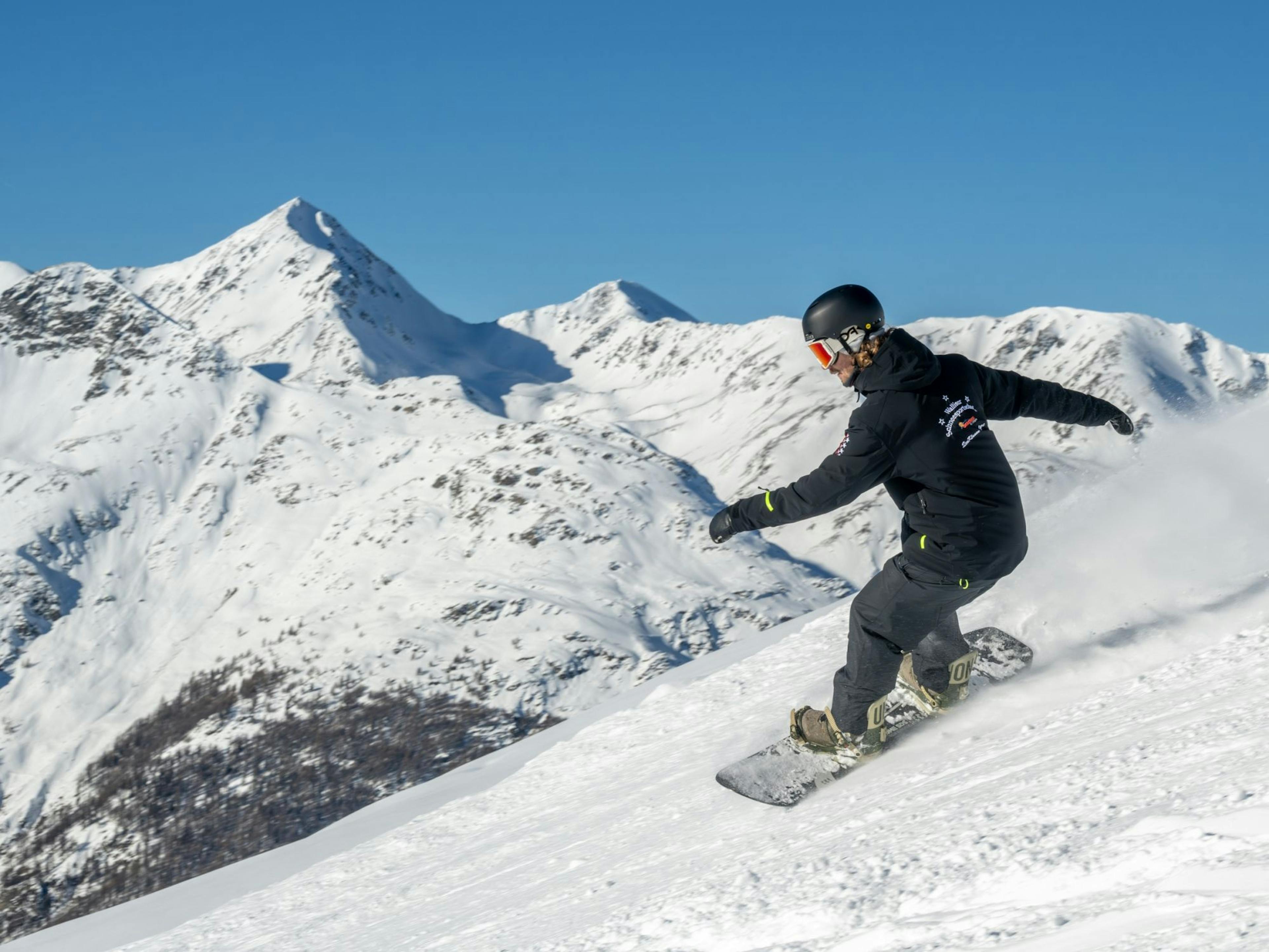 Aulas de snowboard em Hannigalp com uma deslumbrante paisagem montanhosa no inverno.