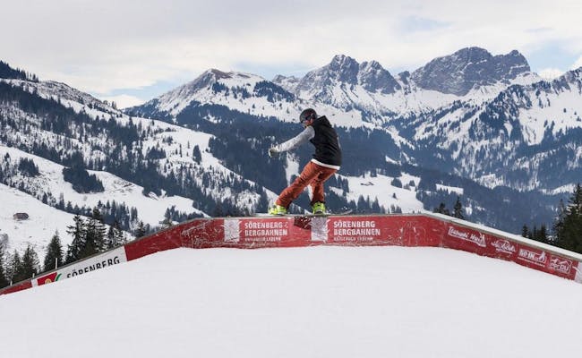 Ski Freestyle at Brienzer Rothorn, snowboarder on rail in snow-covered landscape.