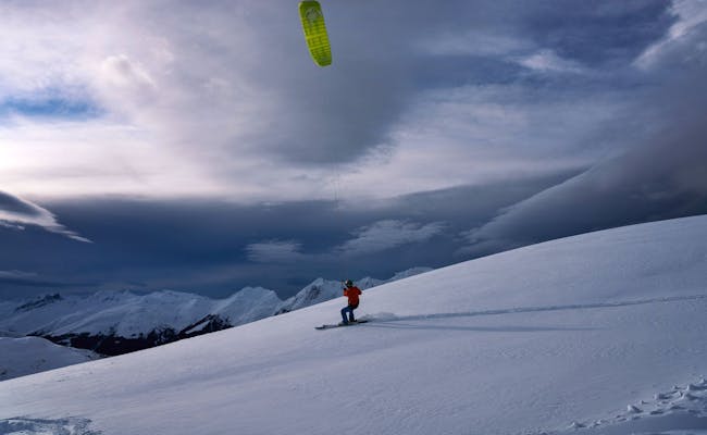 Snowkiting w Pischa w Davos, sportowcy zimowi z latawcem i nartami na zaśnieżonym stoku.