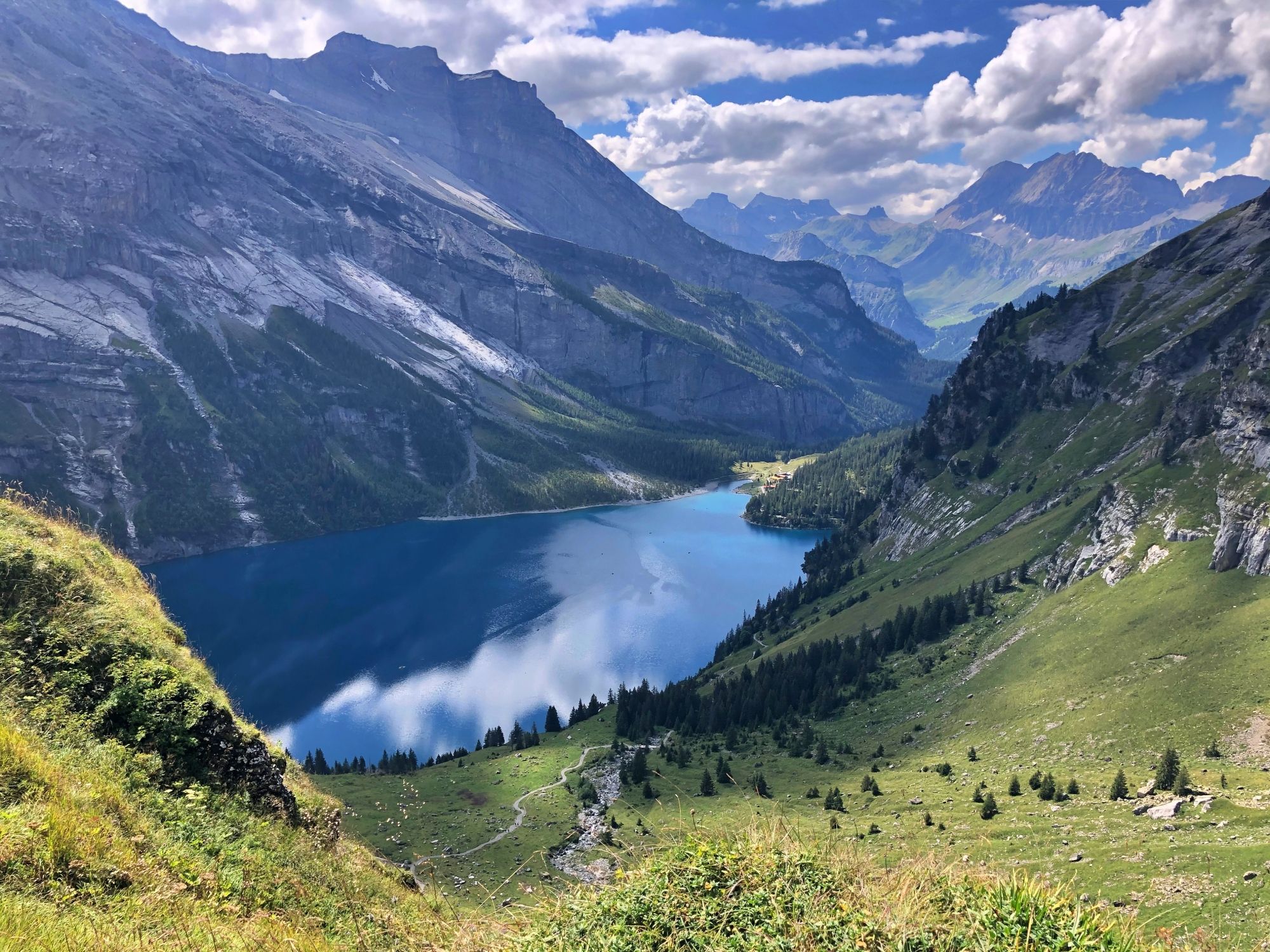 Oeschinensee: vista sul panorama montano, pendii verdi, lago blu e cielo sereno.