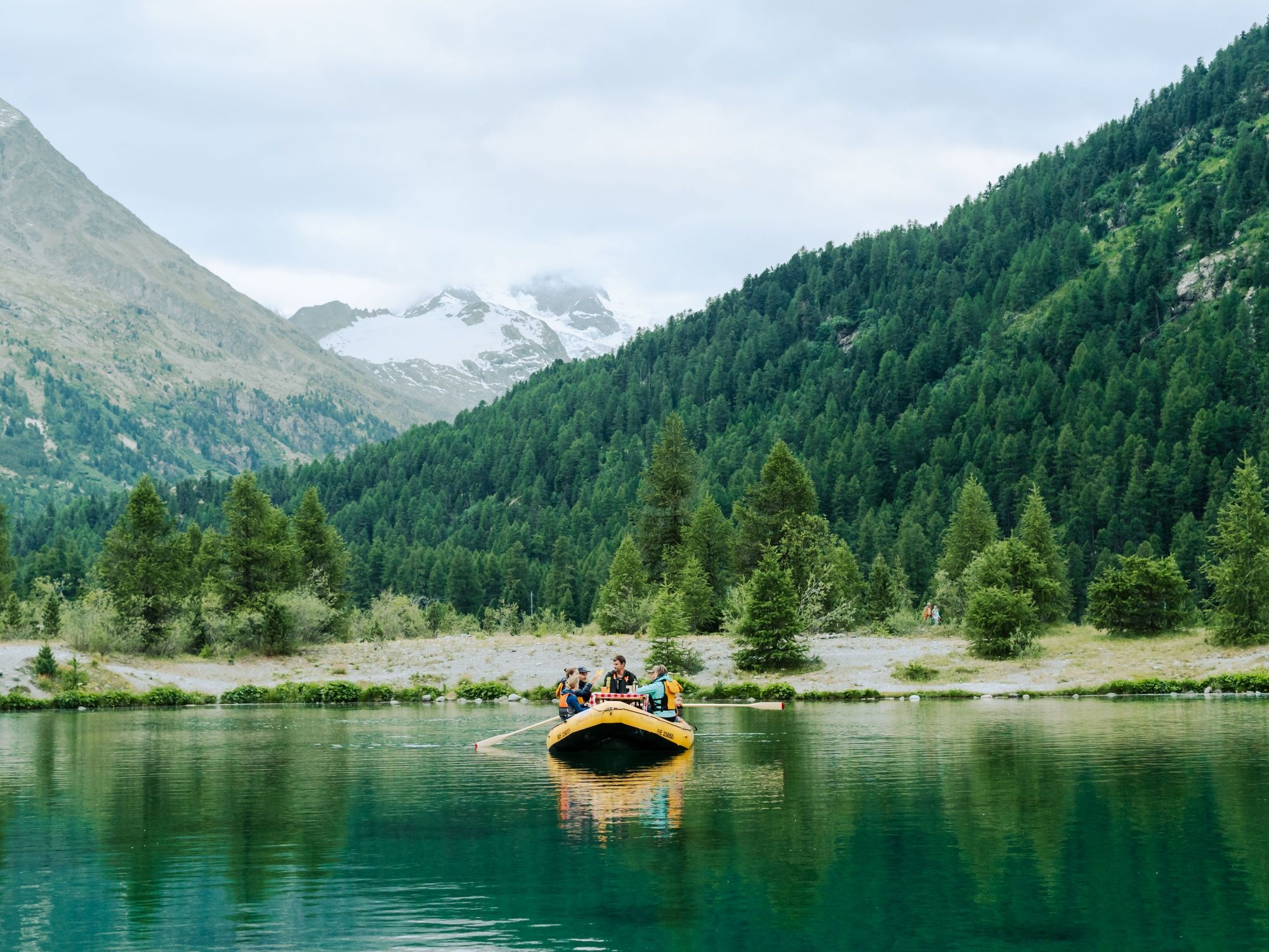Raclette meal by the lake in Switzerland with mountain views and friends, ideal for group activities.
