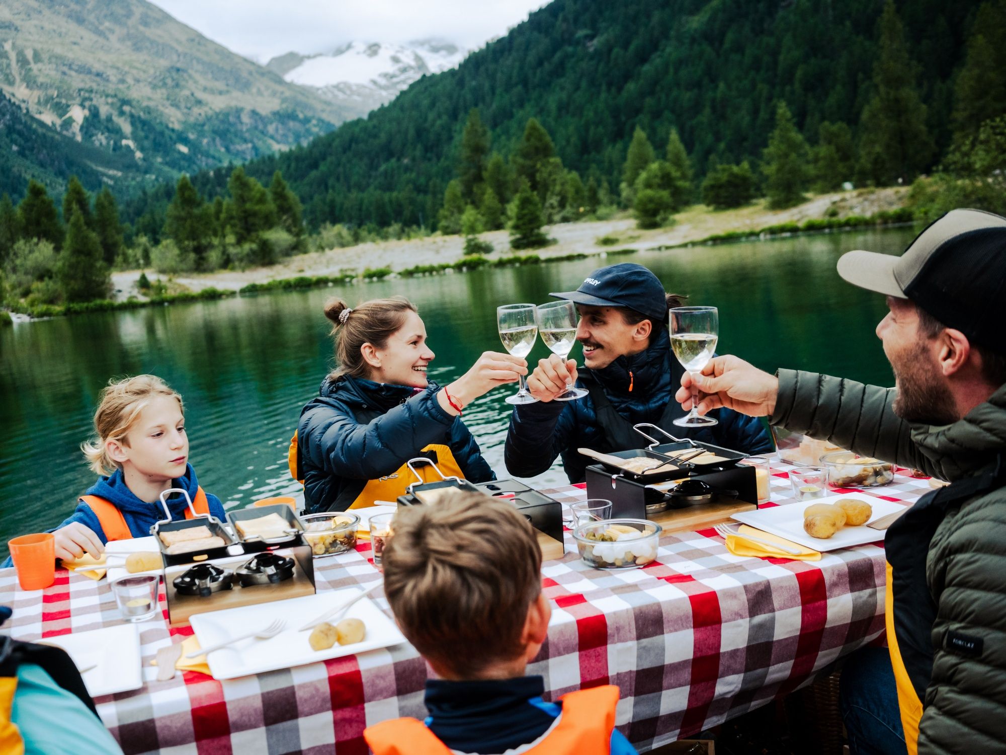 Raclette by the lake with friends at a cozy picnic in nature.
