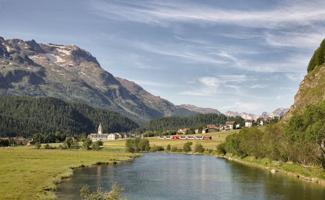 Glacier Express i Engadin kører langs floden under solskin.