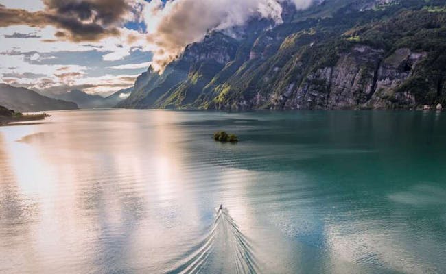 Walensee con barco de agua, rodeado de montañas y nubes.