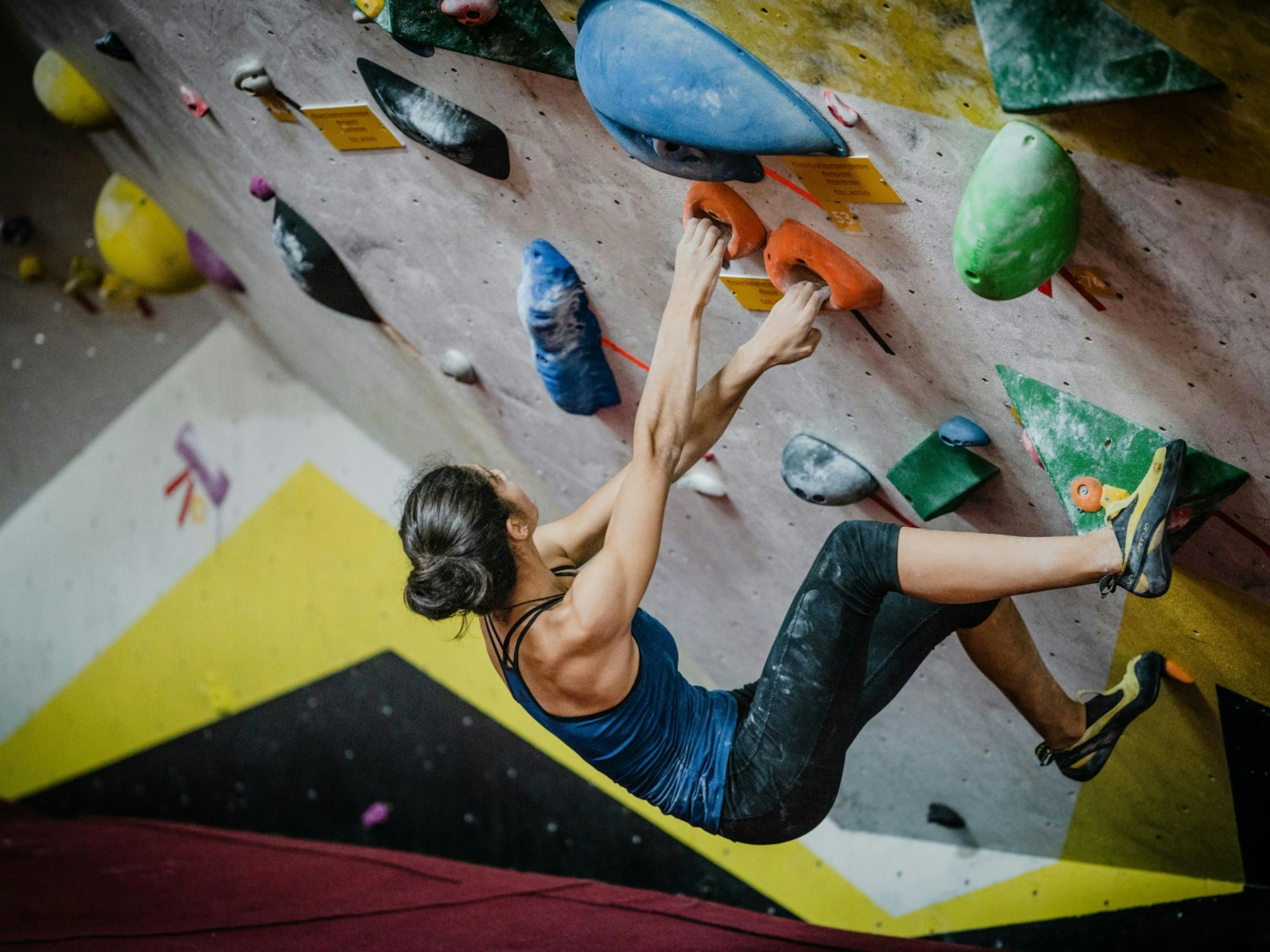 Bouldering: Kletterin in Sporthalle beim Klettern, Fitness, Herausforderungen, Indoor-Sport