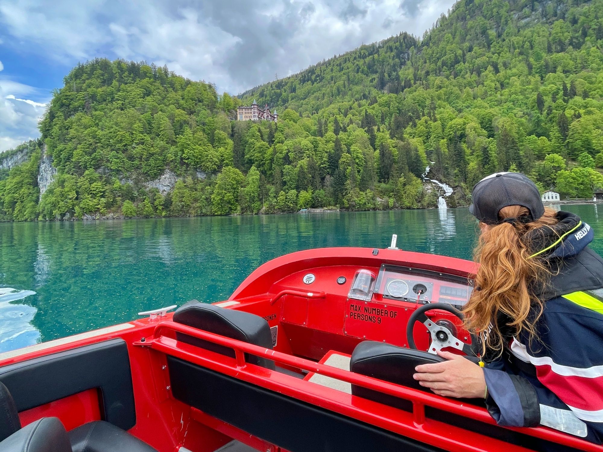 Il jetboat del Lago di Brienz naviga sull'acqua cristallina lungo la riva. Montagne verdi sullo sfondo.