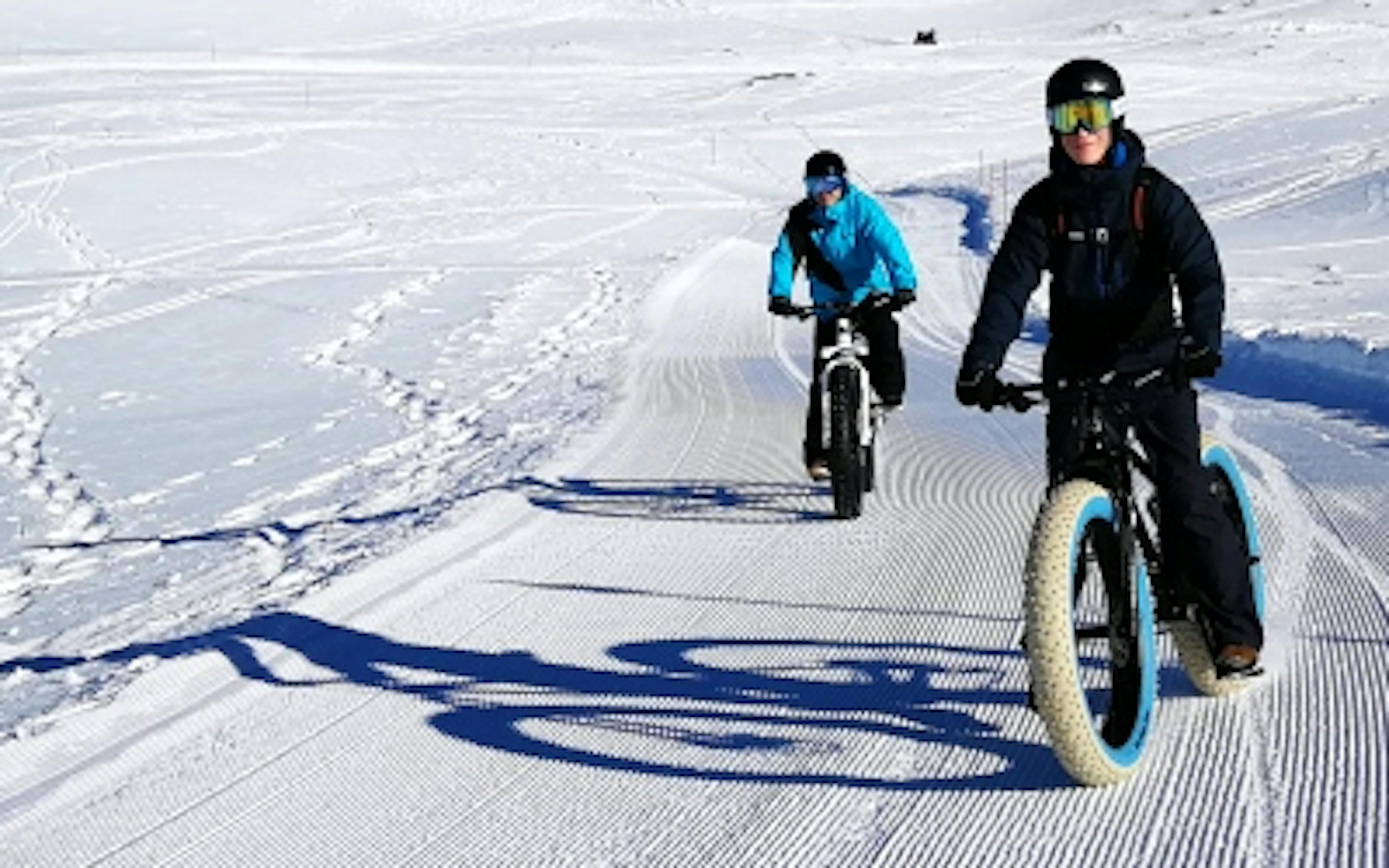 Tour en fatbike à Davos en hiver avec deux conducteurs sur un chemin enneigé.