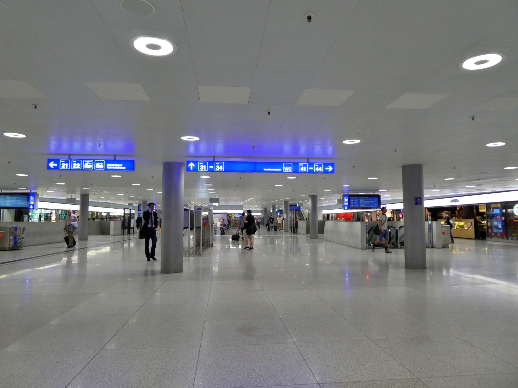 Tiefenbanegård Zürich med moderne skærme og rejsende.