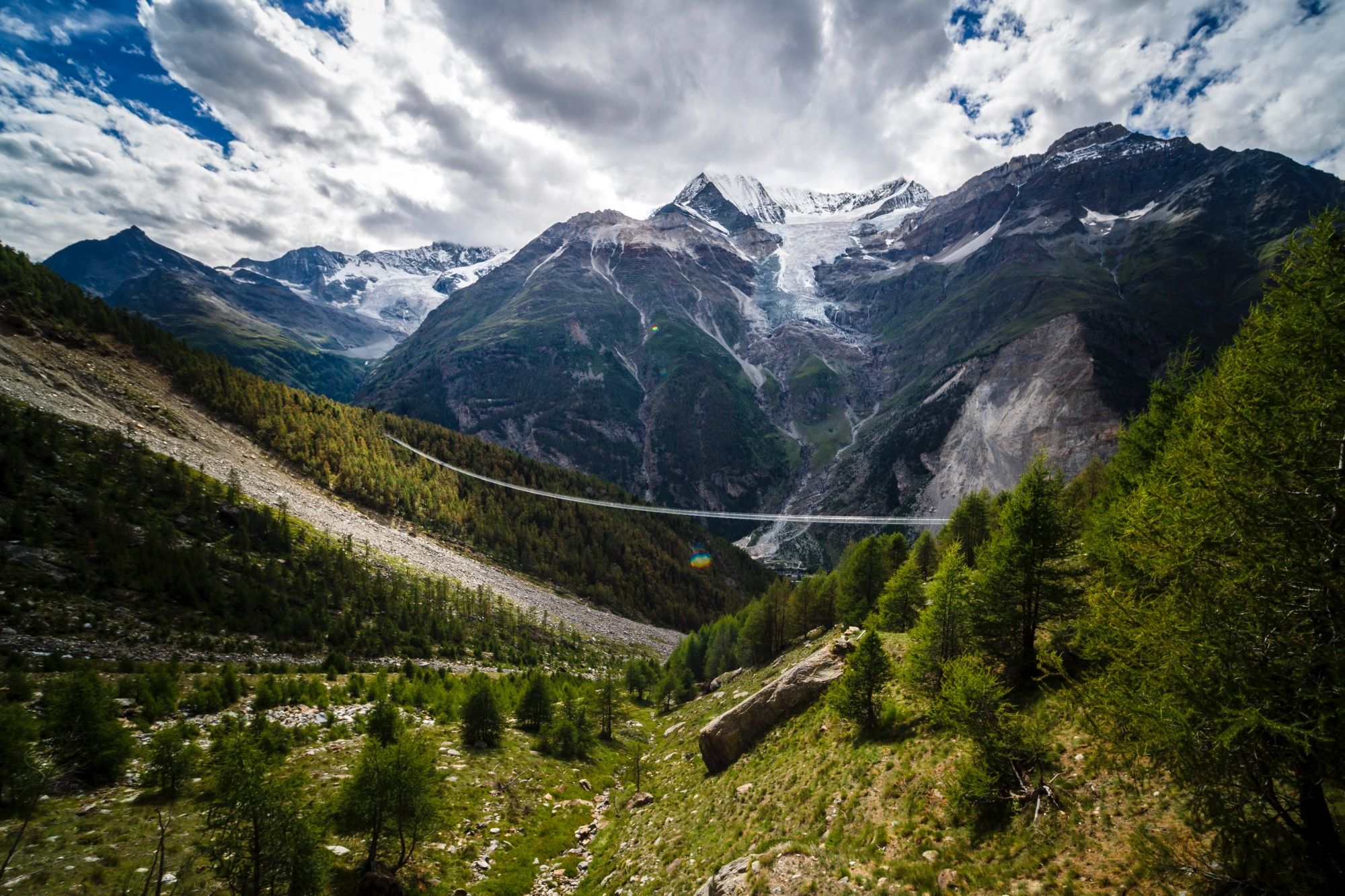 Charles Kuonen Bridge over the valley with mountain glow and mountain panorama in the background.