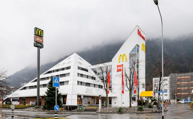 Hotel Ibis Chur diante de um edifício moderno e nevoeiro