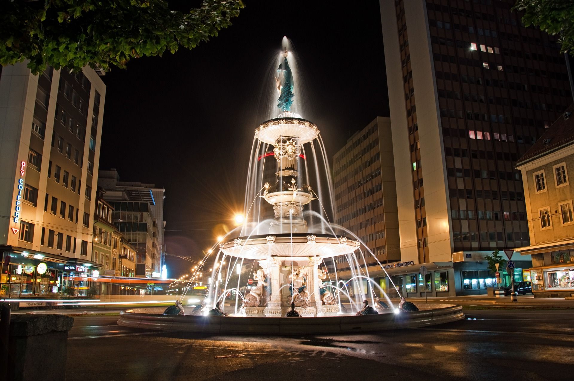 Fountain in La Chaux-de-Fonds with bubbling water, surrounded by modern architecture and lighting atmosphere
