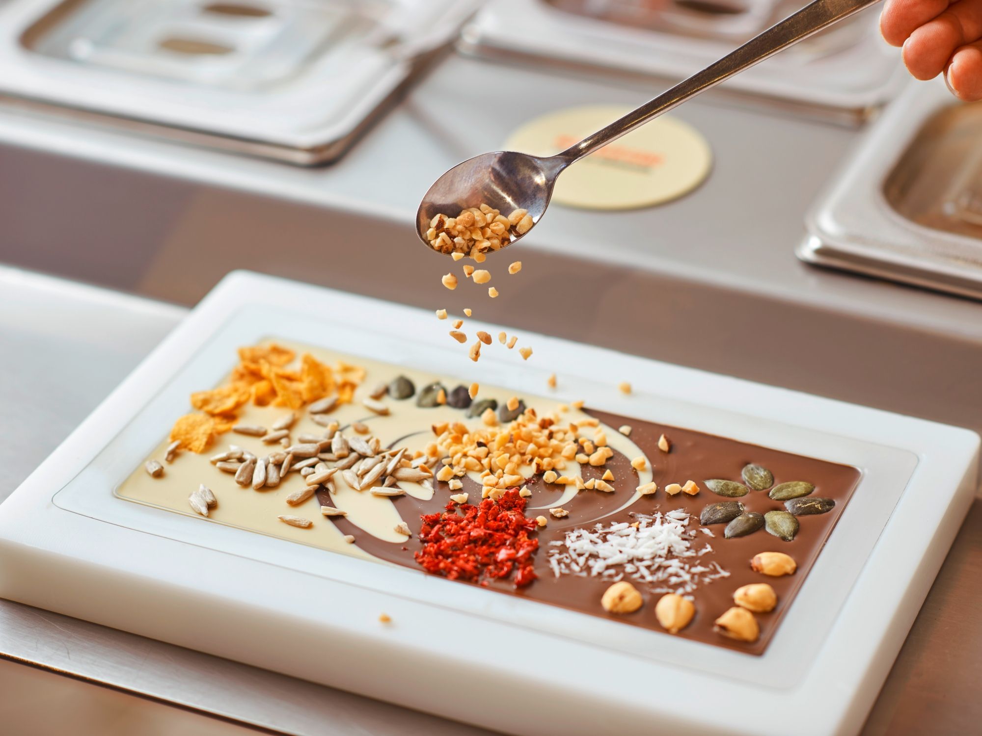 Décorer une tablette au Chocolarium Flawil avec des noix, des fruits et du chocolat