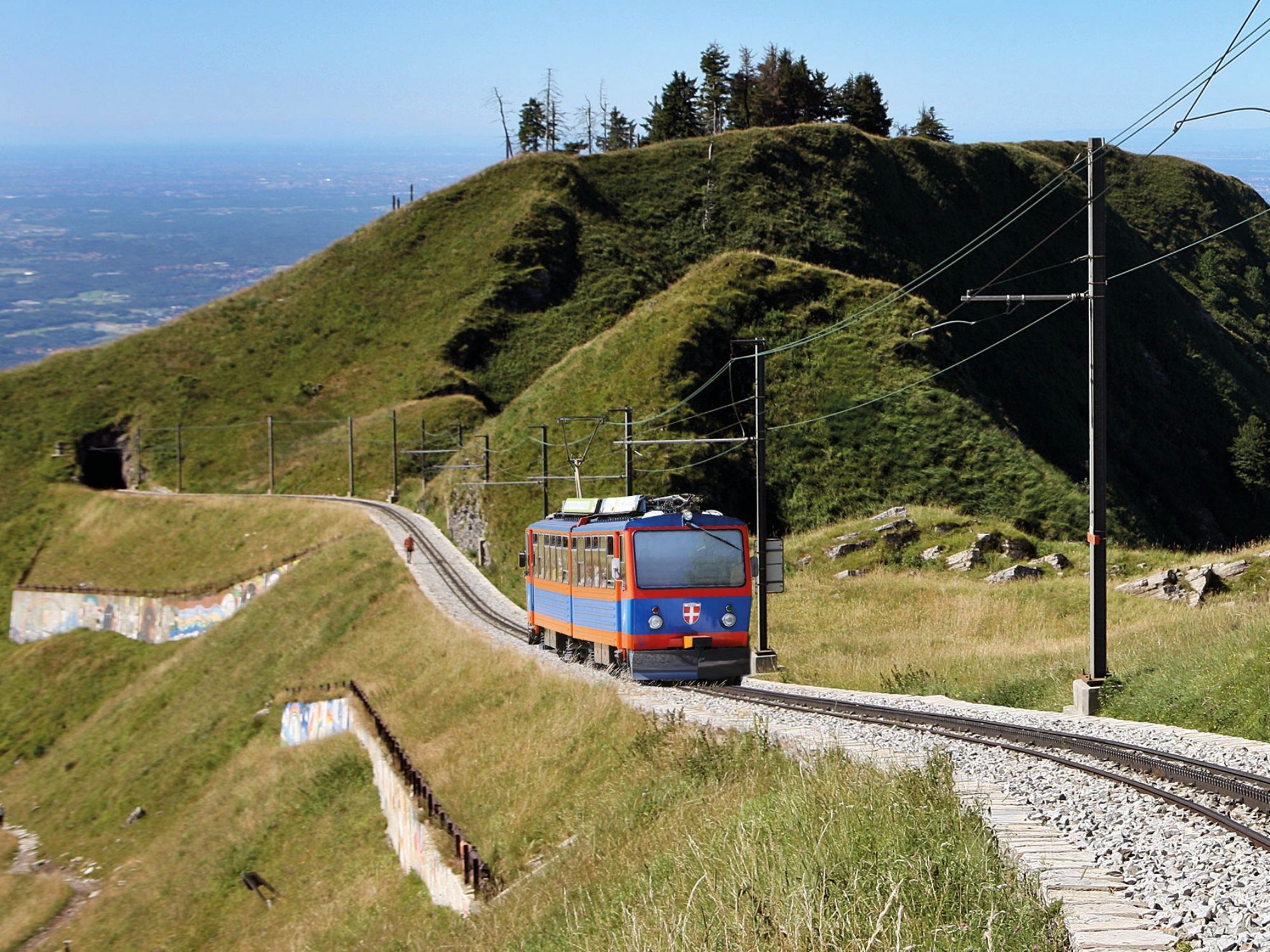 Monte Generoso: A train passes by green hills in the summer landscape of Switzerland.