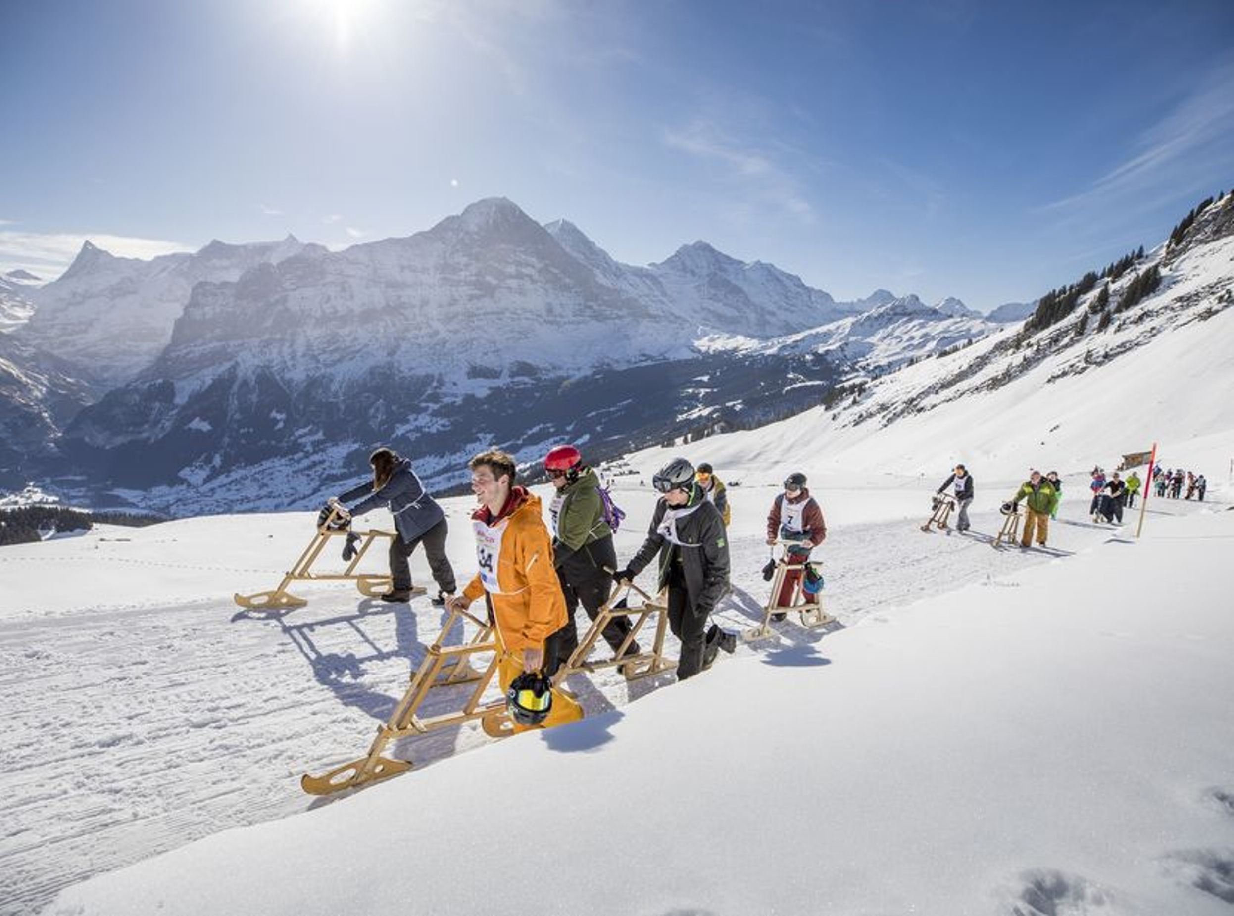 雪の中のヴェロゲメル、乗っている人々、背景に山々。