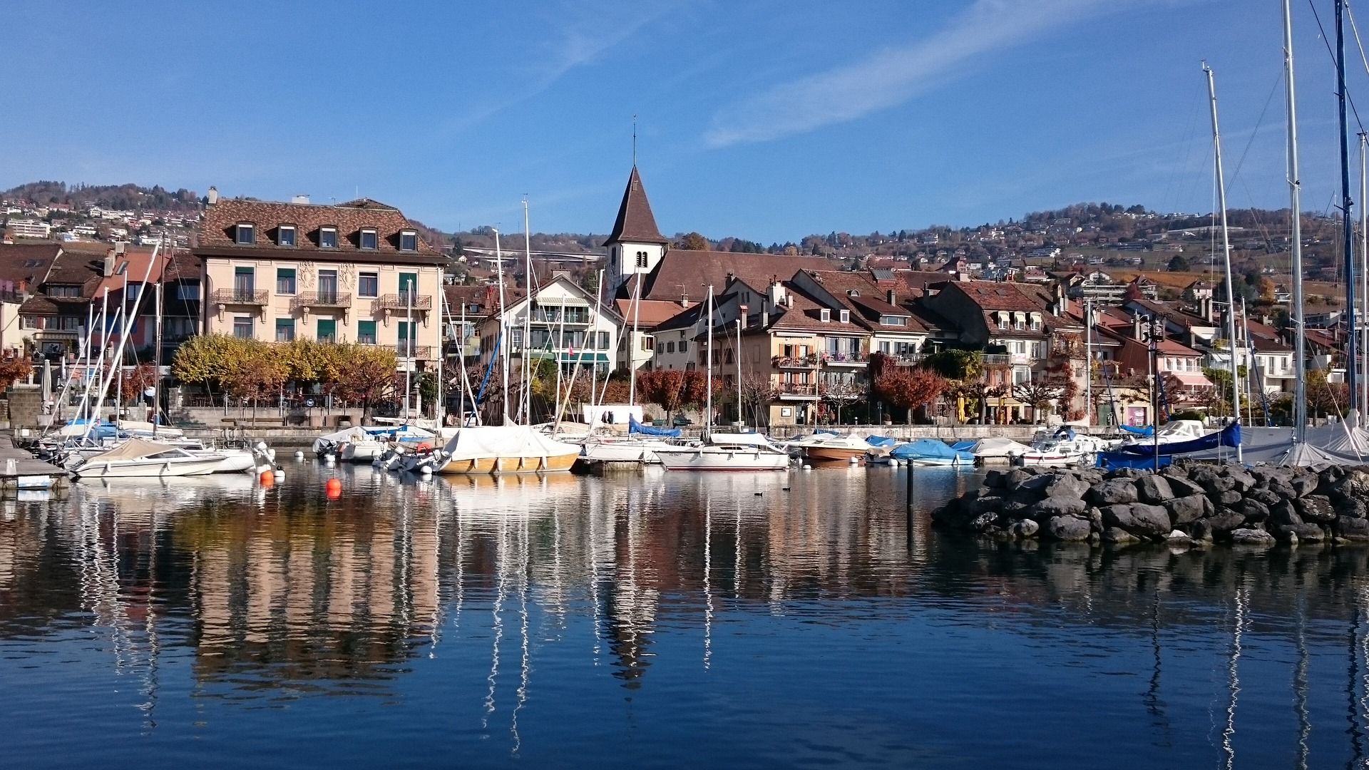 Lausanne harbor with yachts and picturesque houses by Lake Geneva, ideal for relaxing days.