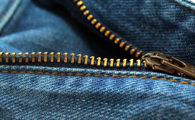 Le zip sur le jean bleu montre des détails fonctionnels.
