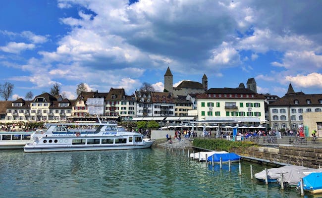 Ferry în portul Rapperswil, priveliște idilică asupra lacului cu arhitectură istorică și activități pe apă.