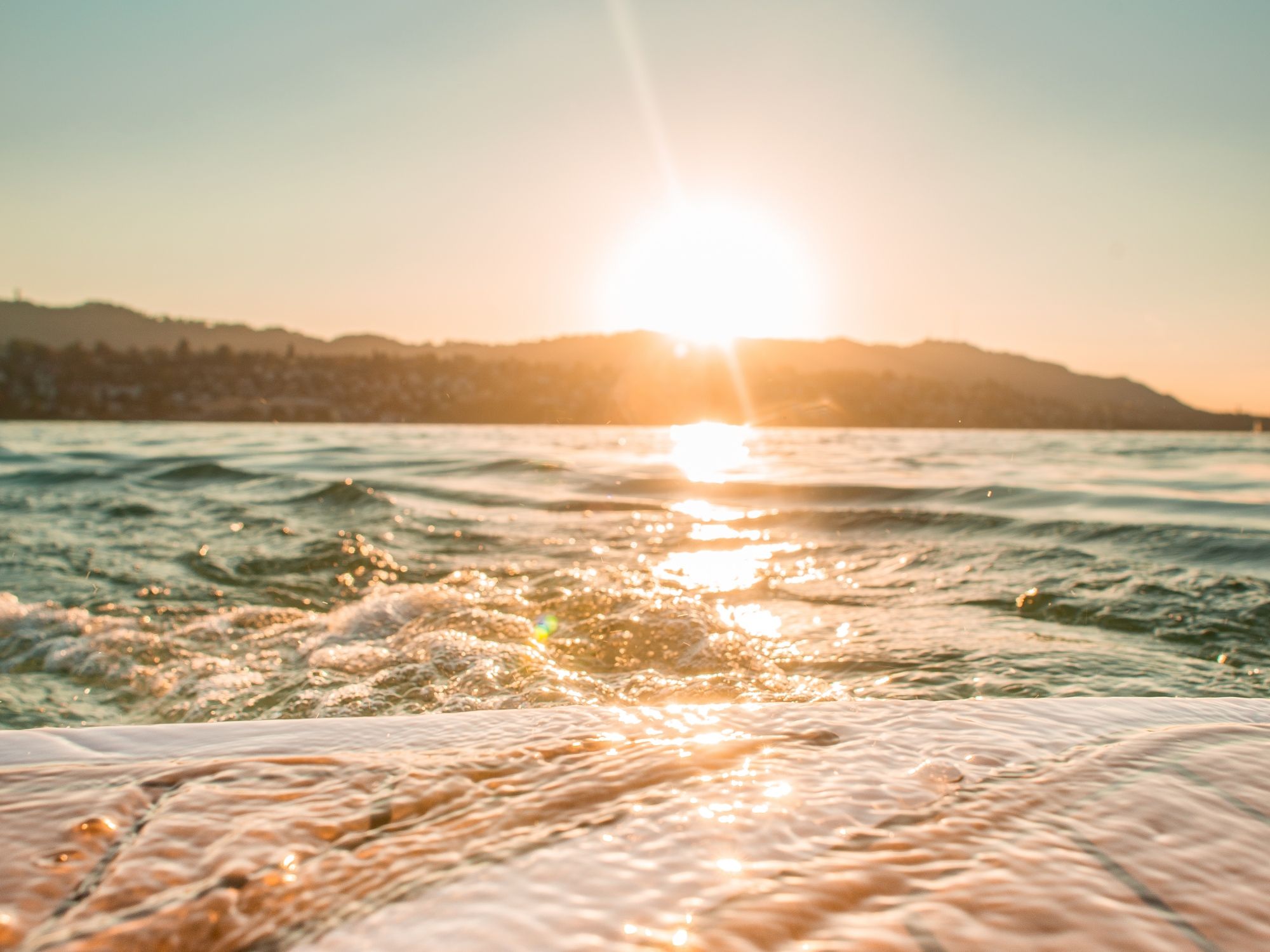 Wakesurfen am Zürichsee: privates Boot, sonnige Atmosphäre und entspannte Wasseraktivitäten im Sommer.