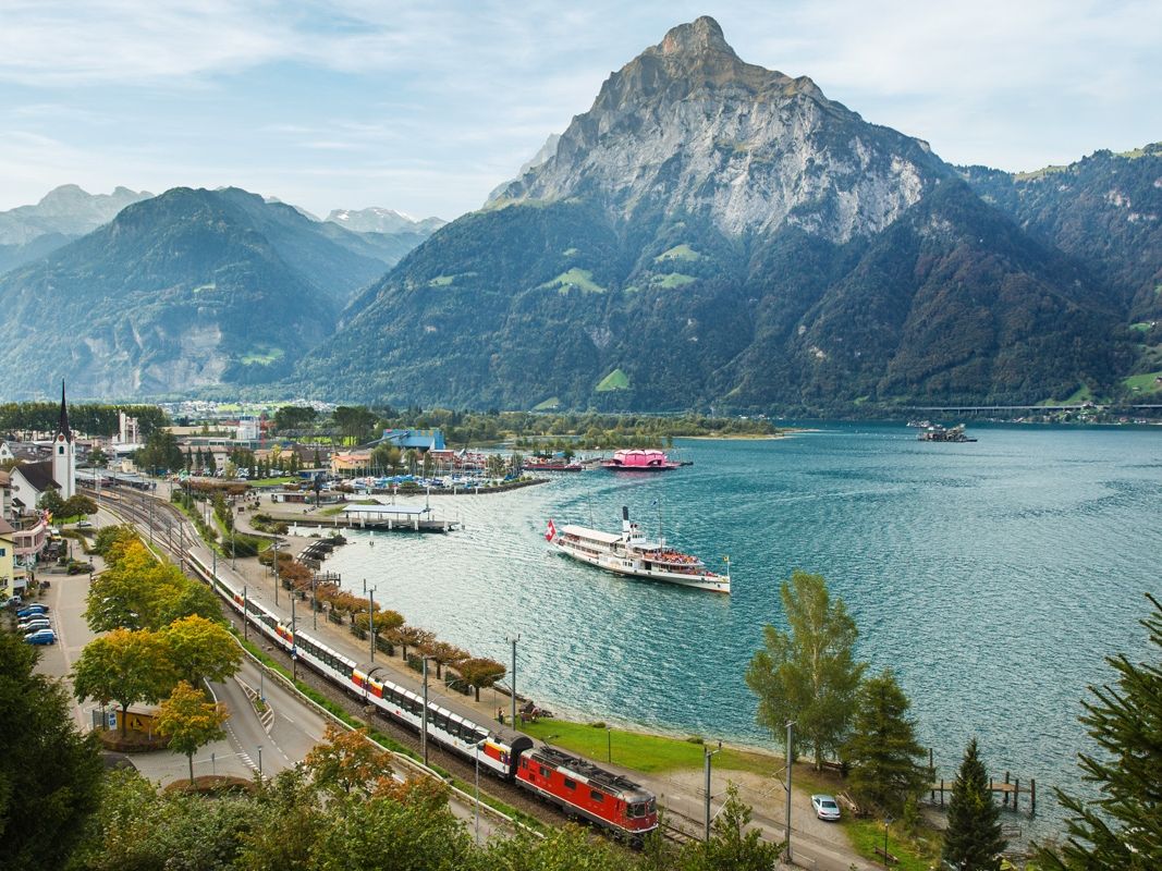 Gotthard Panorama Express travels along Lake Lucerne with mountains in the background.