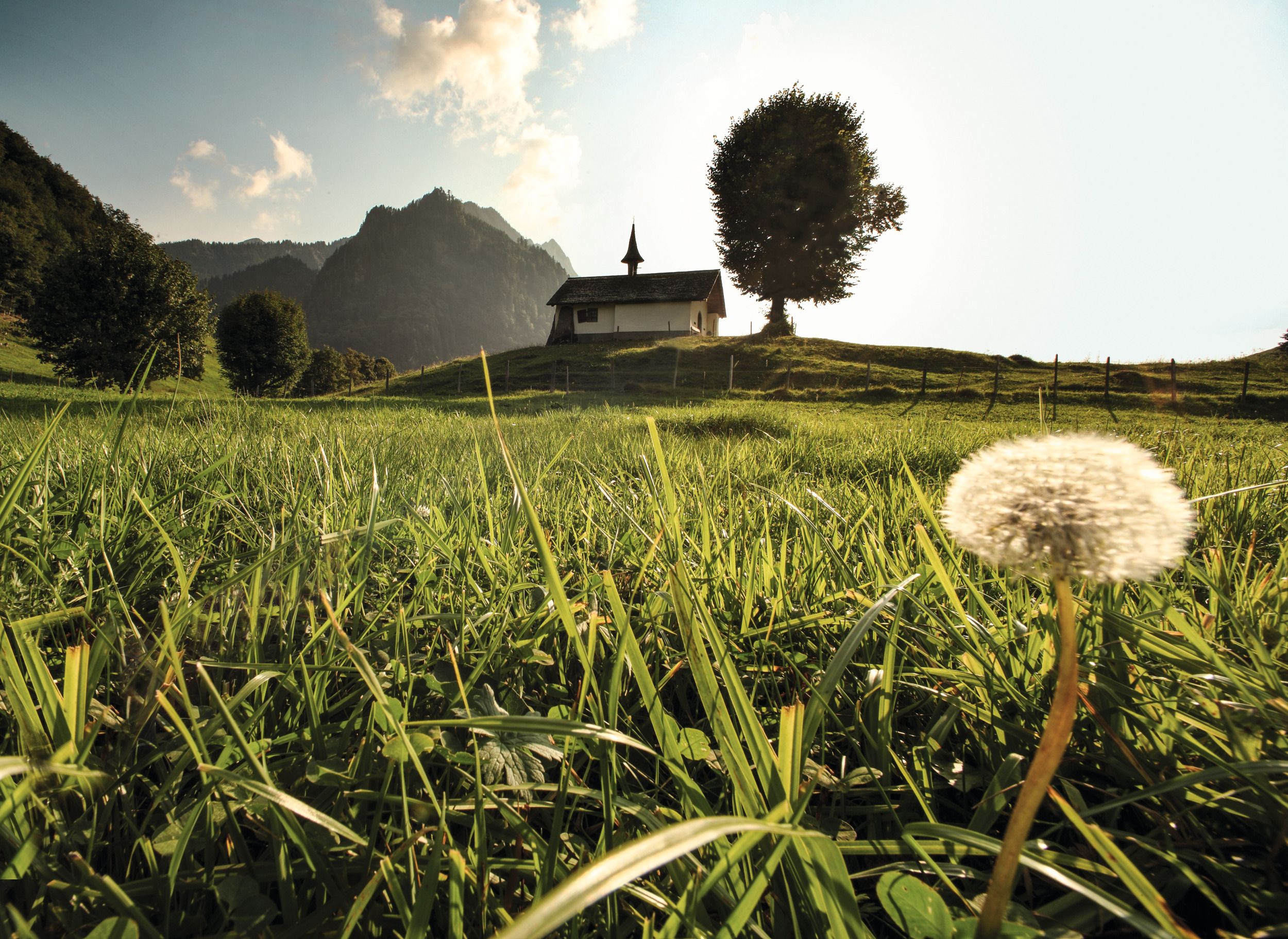 Kaple v Gruyère před hornatou krajinou s zelenou trávou