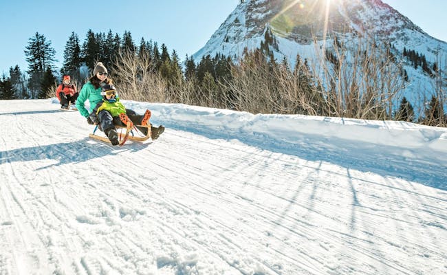 Moleson Skigebiet: Familias trineo en la pista bajo el sol.