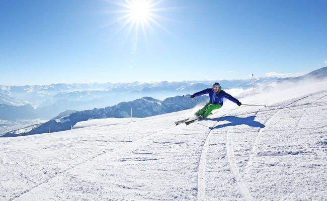 Curso de Esquí Pizol con esquiadores en una pista cubierta de nieve bajo el sol