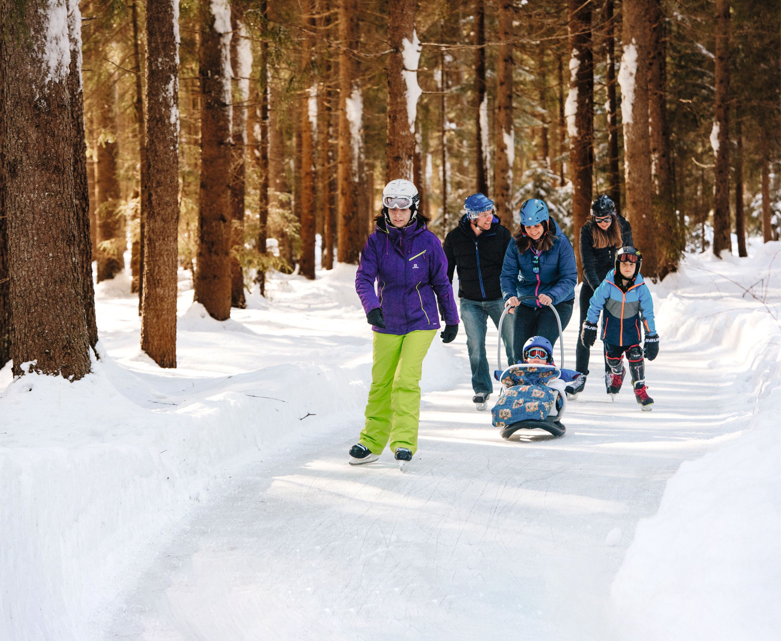 Bruslení na přírodní ledové ploše Albula ve sněhu. Zasněžené stromy obklopují ledovou plochu.