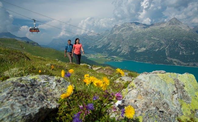 Drumeție la Corvatsch cu lac de munte, pajiști înflorite și peisaje impresionante în Engadin.