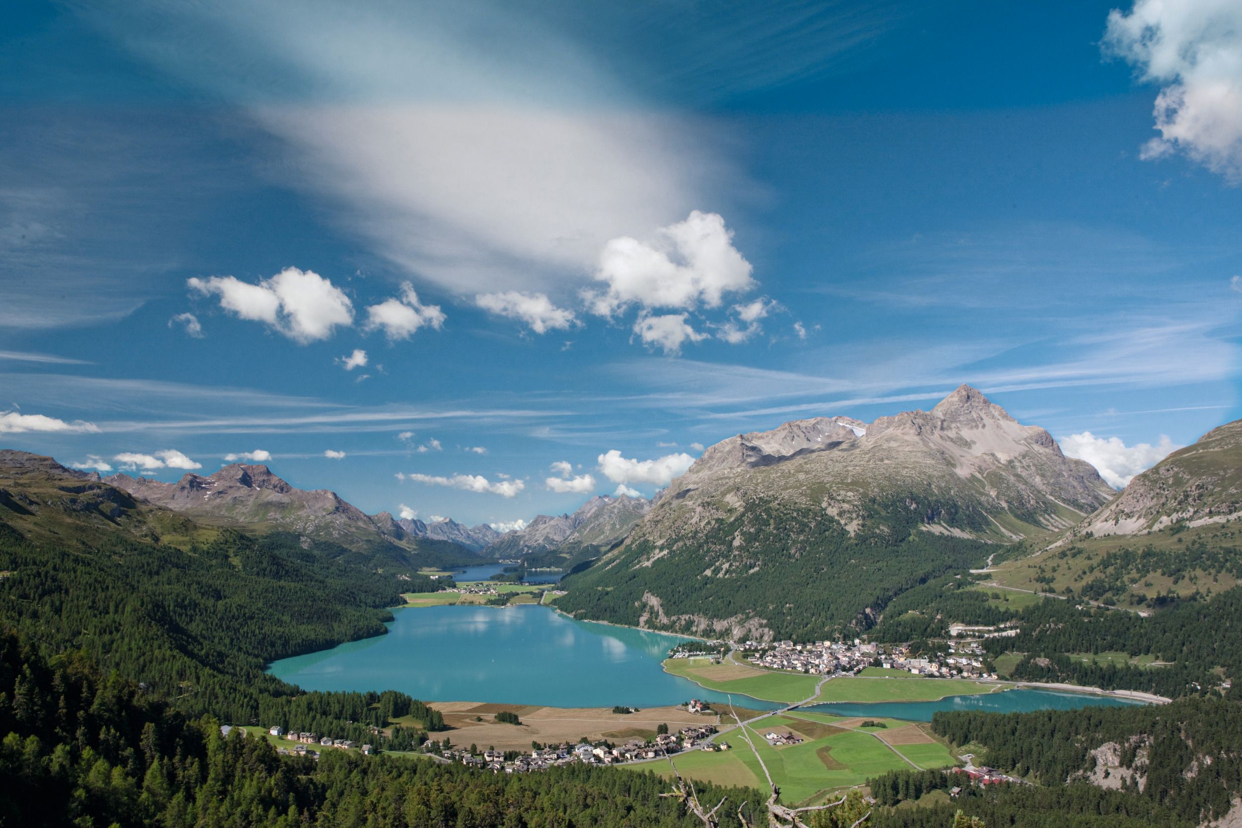 Panorama del Lago di Silvaplana con montagne, boschi e cielo blu chiaro in Svizzera.