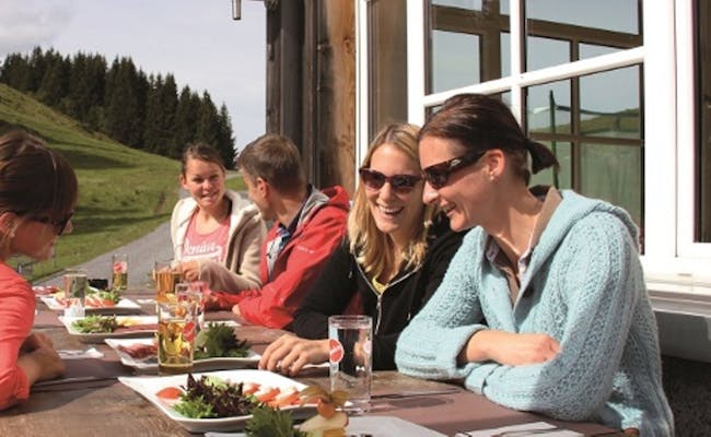 Grupo de personas que comen y beben en la Molseralp, con prados verdes de fondo