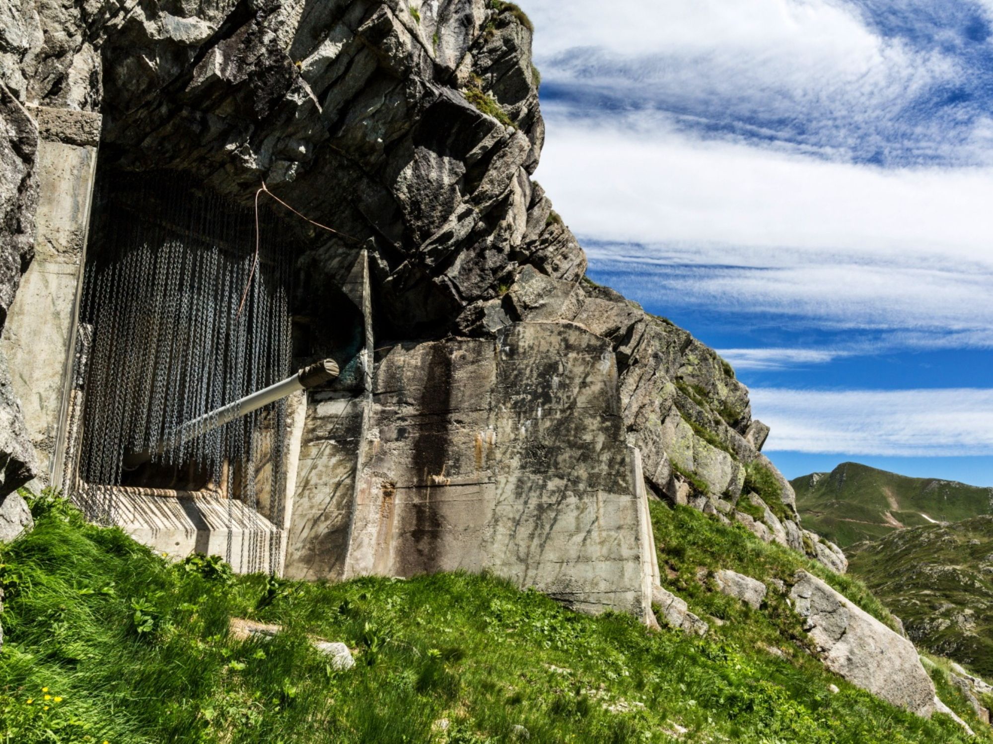 San Gottardo : formations rocheuses impressionnantes et prairies verdoyantes dans le paysage montagneux.