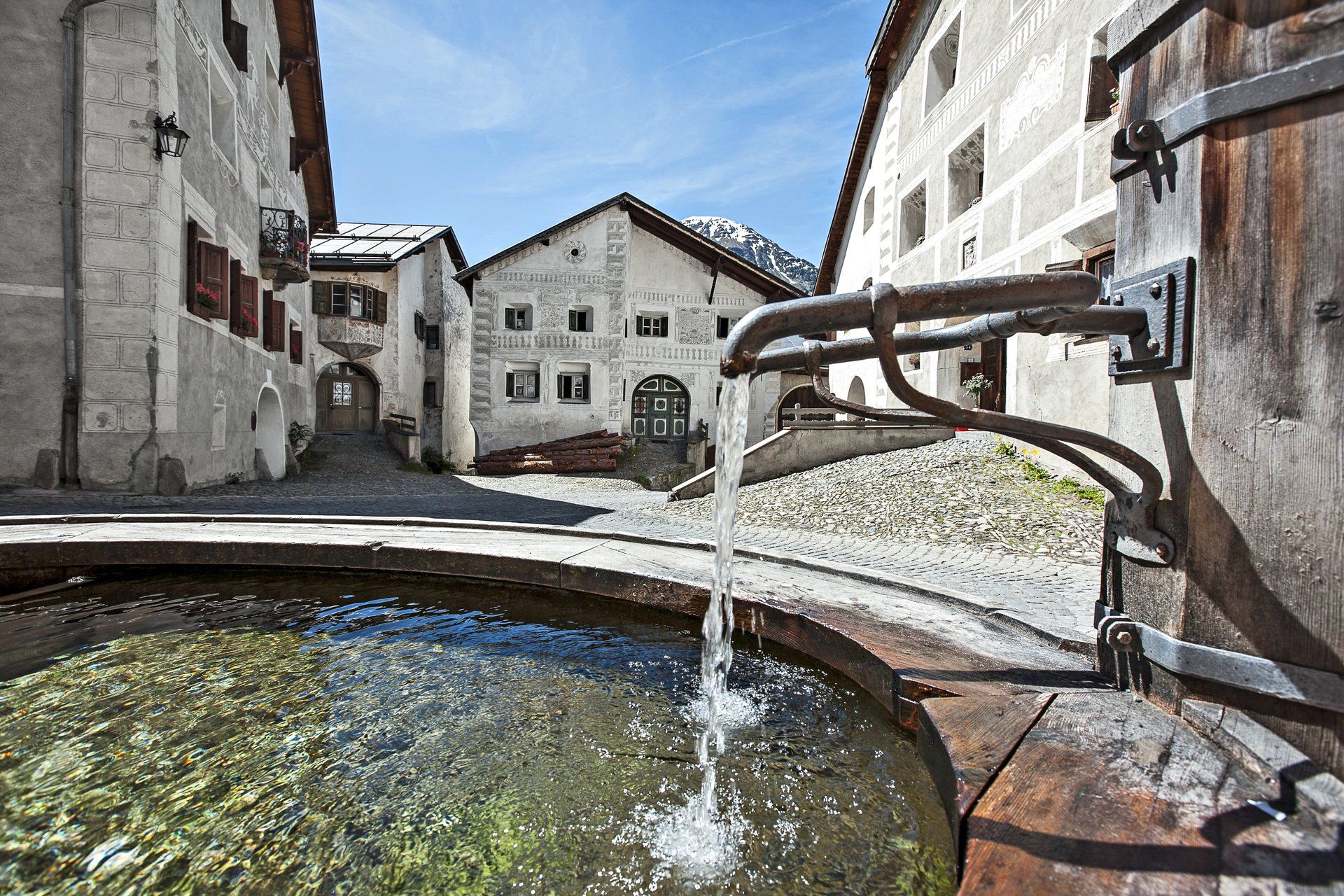 Fontijn in het dorpscentrum van Guarda met historische gebouwen en een heldere lucht.
