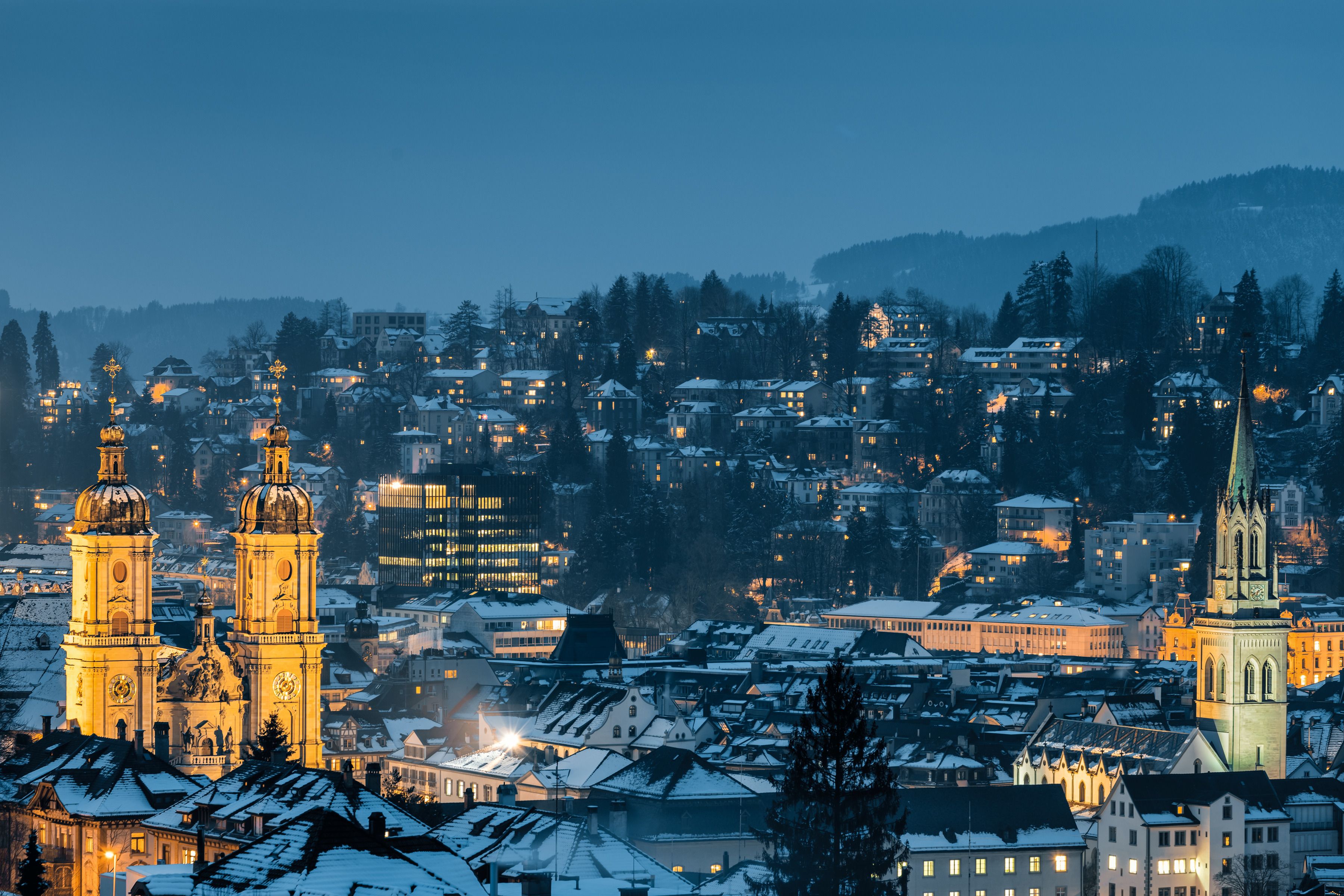 St. Gallen in winter with snow-covered roofs and illuminated churches. Experience the Swiss winter magic.