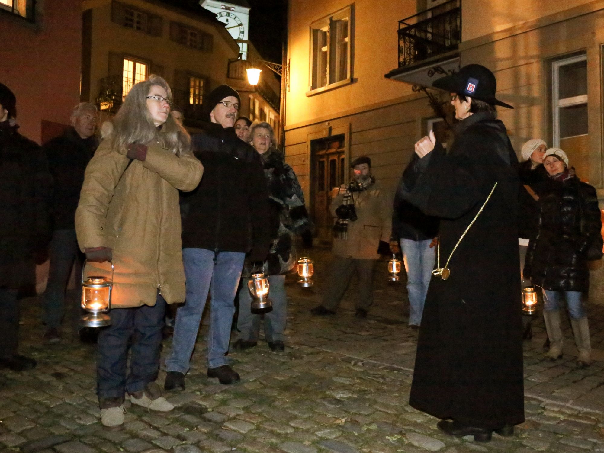 Wycieczka po Chur przy wieczornym oświetleniu, zabytkowe budynki, uczestnicy z latarkami.