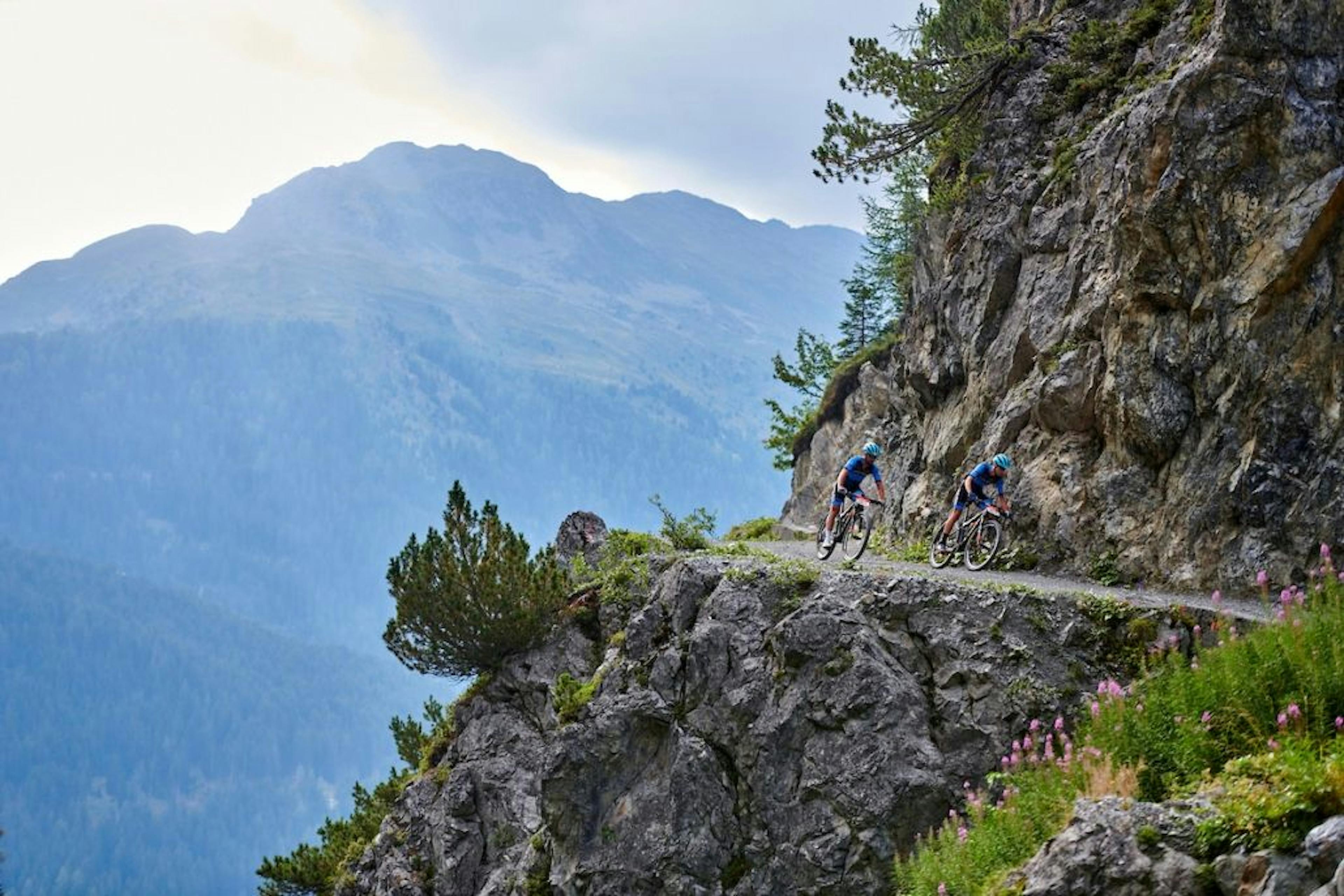 Bike tour on single trail in Davos with bikers in mountain landscape.