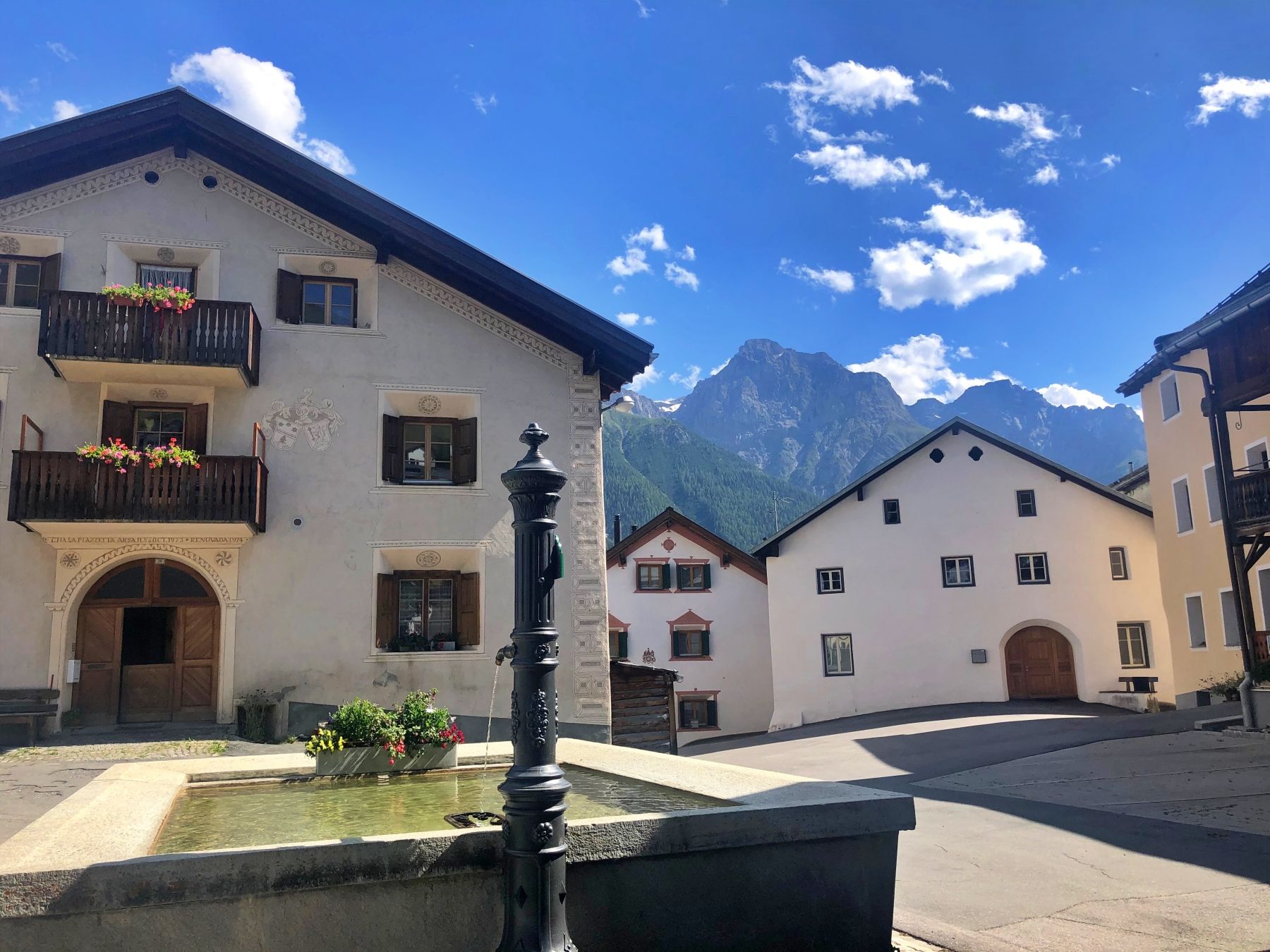 Fontein op het dorpsplein in Sent met schilderachtig uitzicht op de Alpen