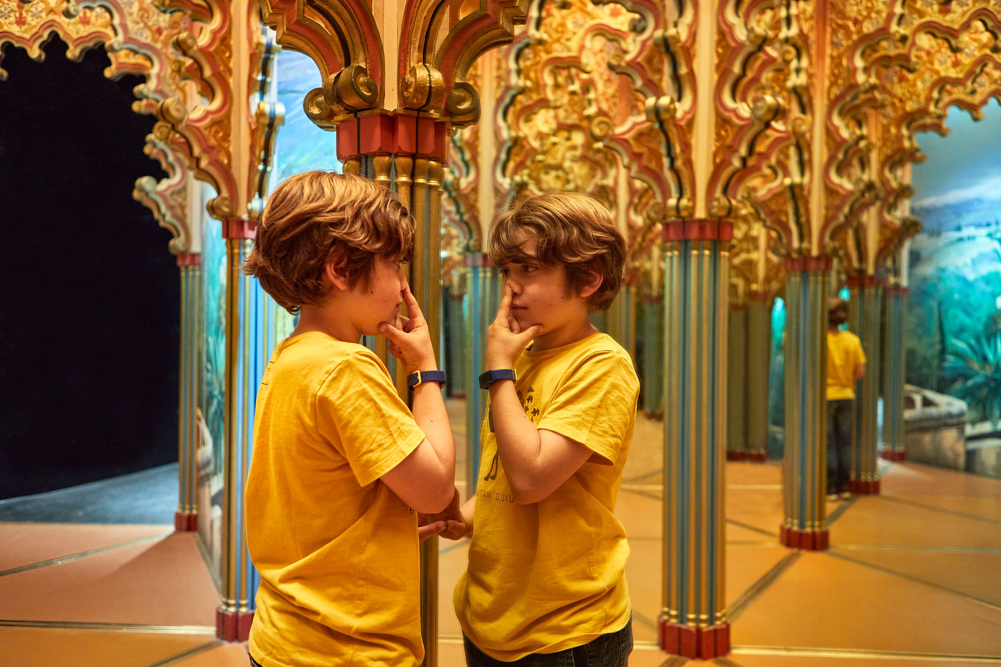 Labirin cermin di taman glasier dengan seorang budak lelaki yang ingin tahu melihat cermin.
