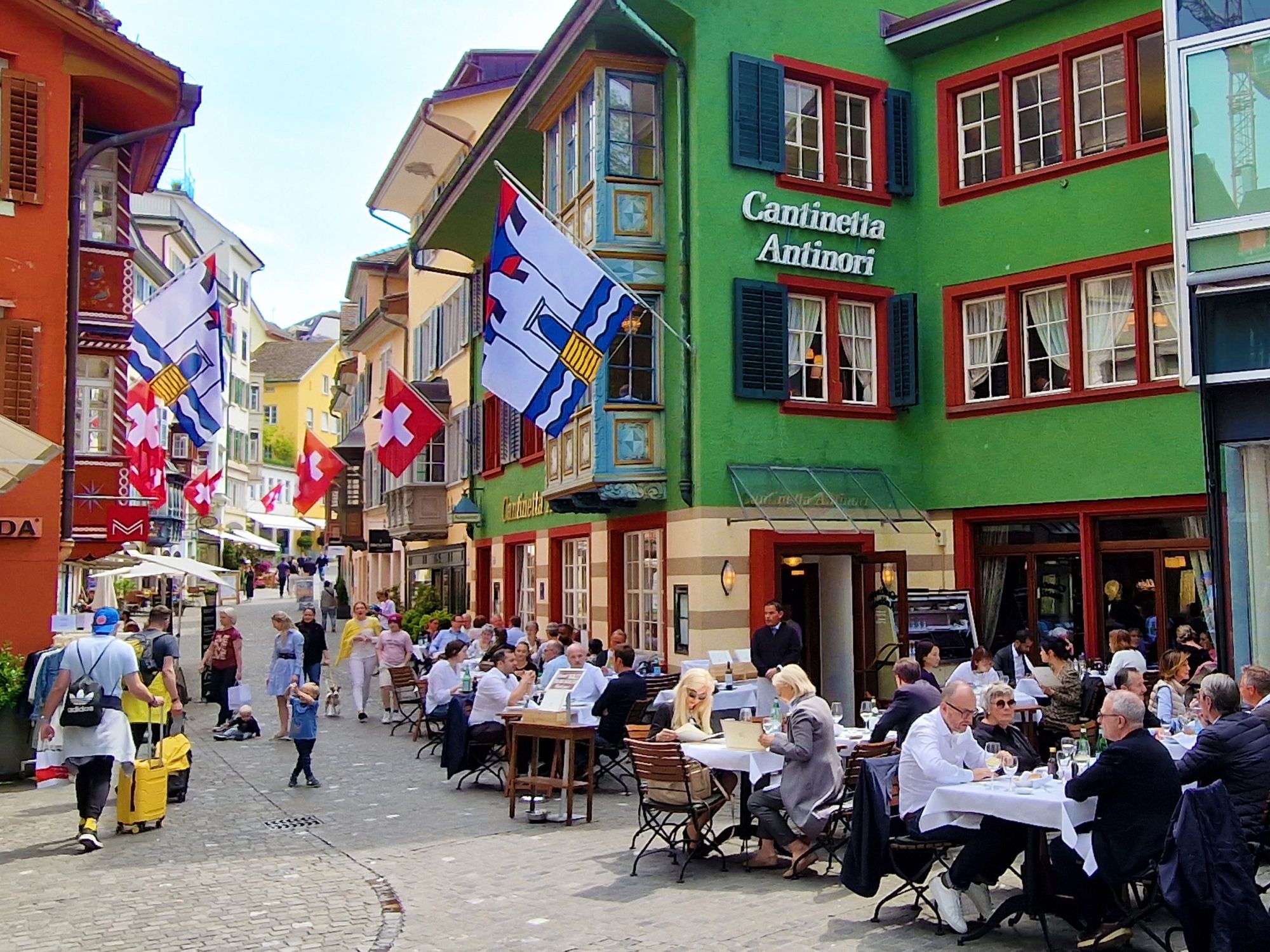 Zürich Innenstadt: malerische Straßenszene mit Restaurants und Flaggen bei einem Tagesausflug.