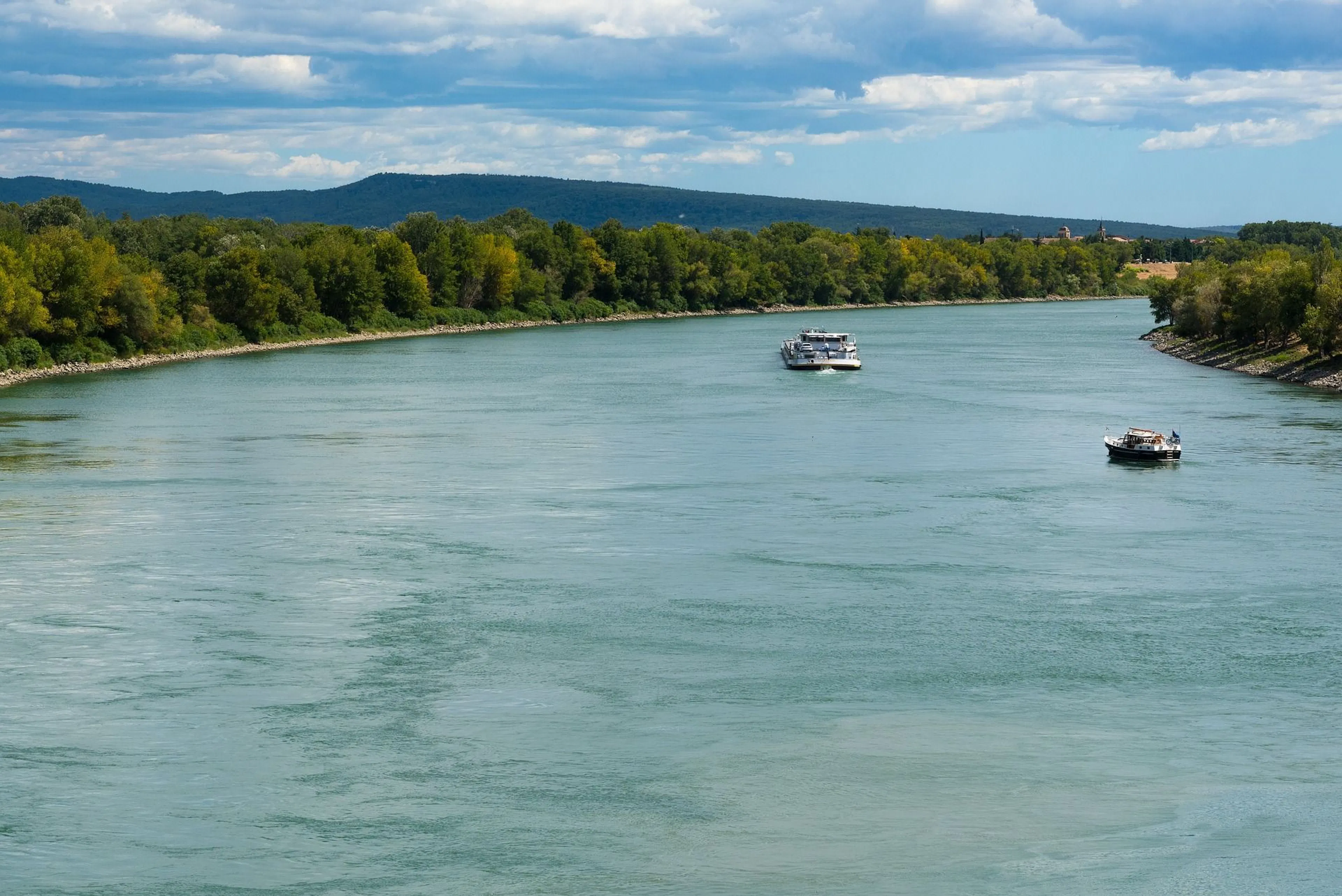 Rhône: Hajók a folyón, zöld természettel és hegyeivel körülvett bájos tájban.