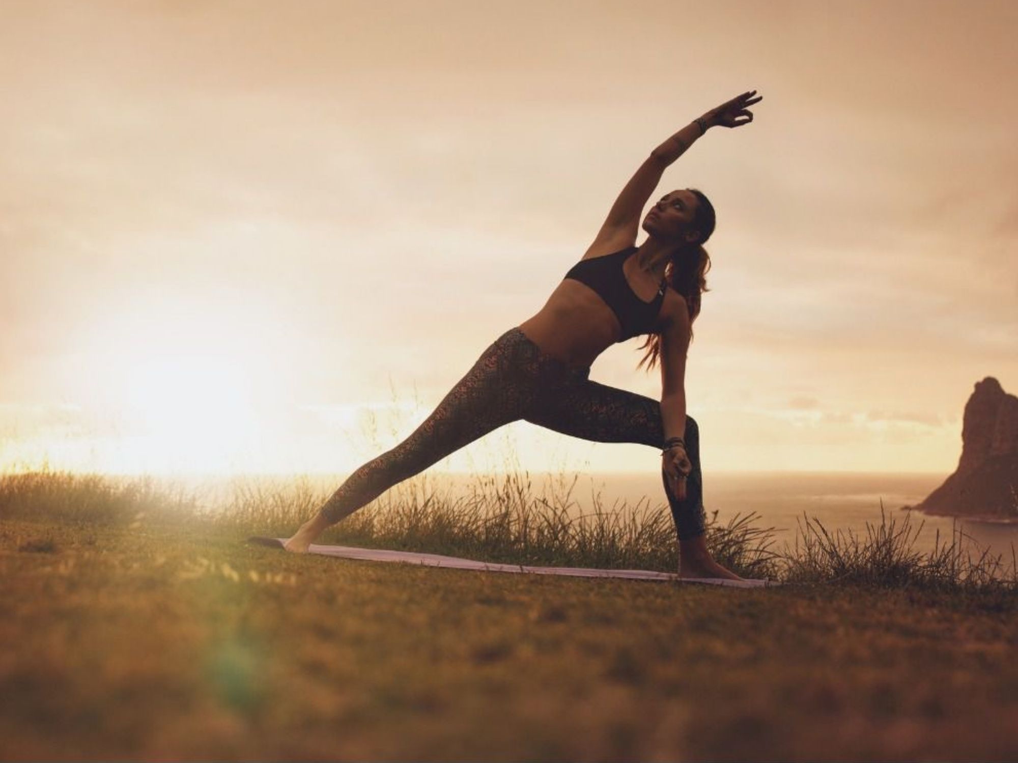 โยคะบนภูเขาในธรรมชาติท่ามกลางแสงแดดยามเย็นที่ส่องสว่าง เหมาะสุดสำหรับการผจญภัยและการผ่อนคลาย.