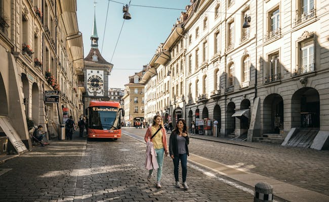 Vieille ville de Berne avec un bus urbain et des touristes en promenade.