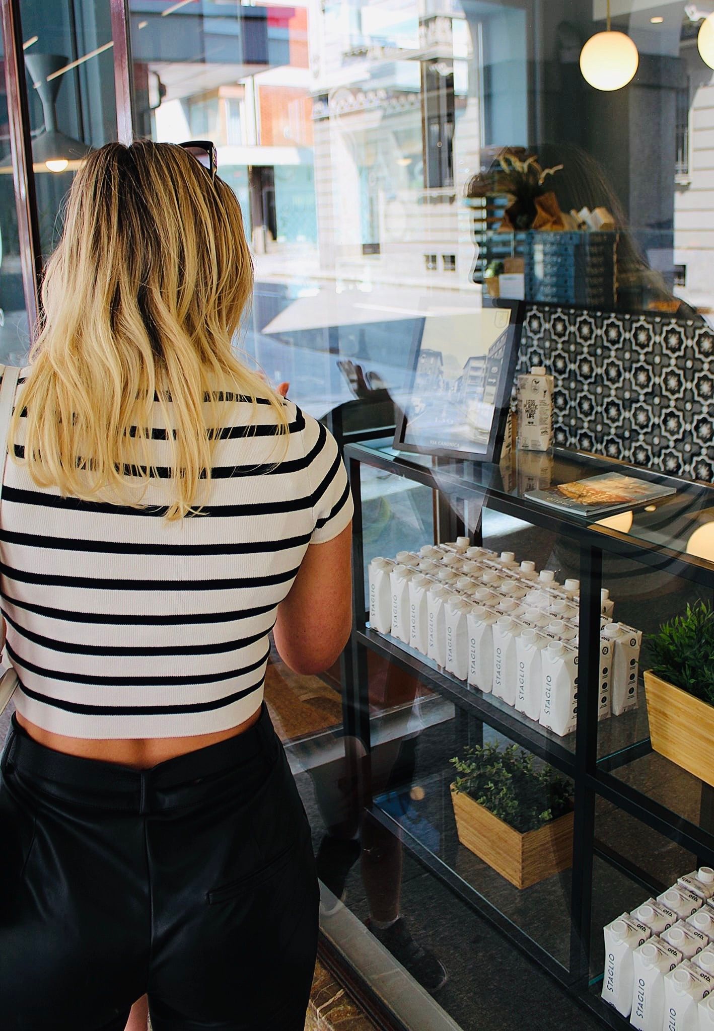 Frau mit gestreiftem Shirt betrachtet Produkte in einem Laden in Lugano