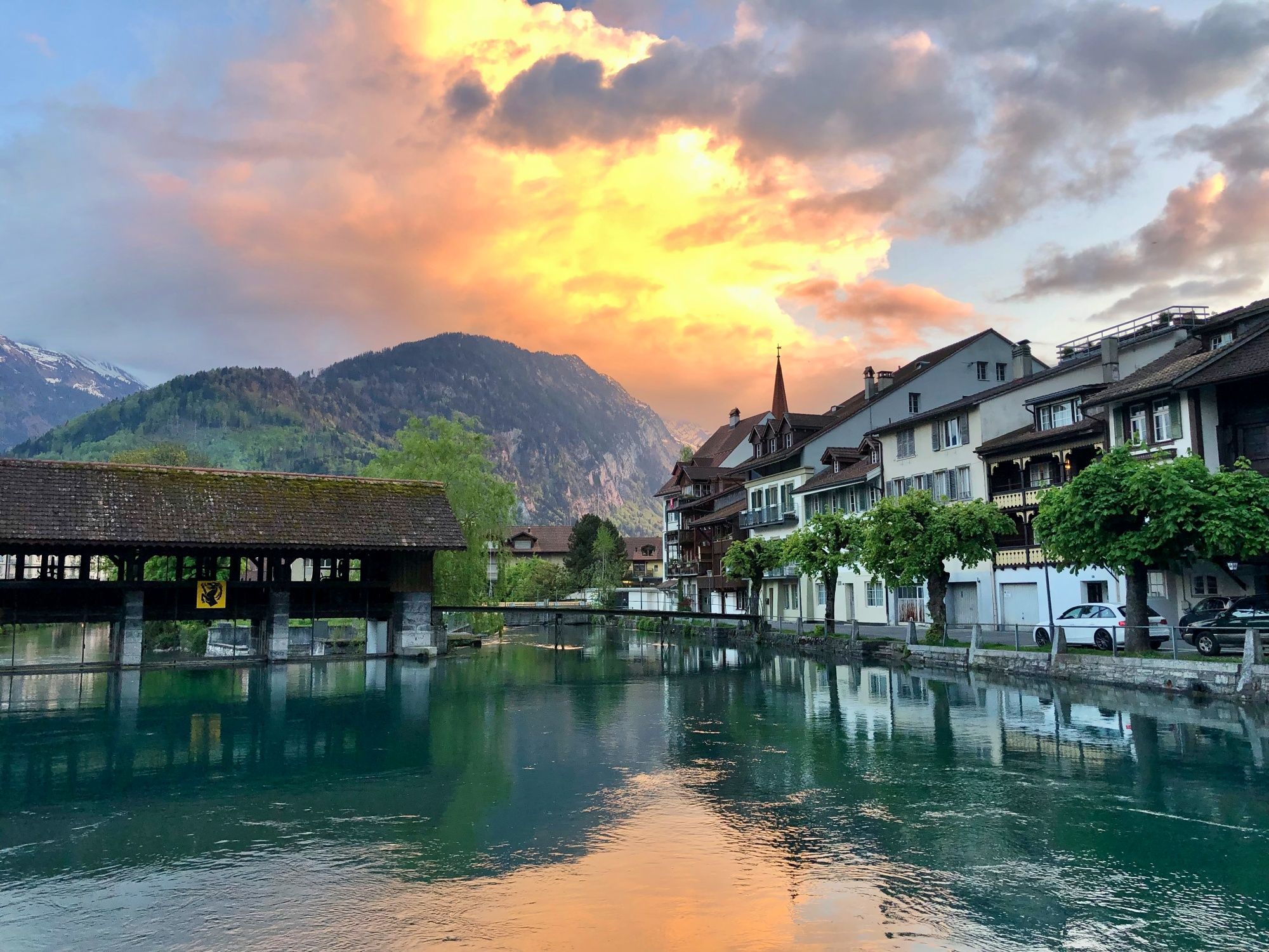 Interlaken: picturesque town landscape with mountains, water, and blooming trees in summer.
