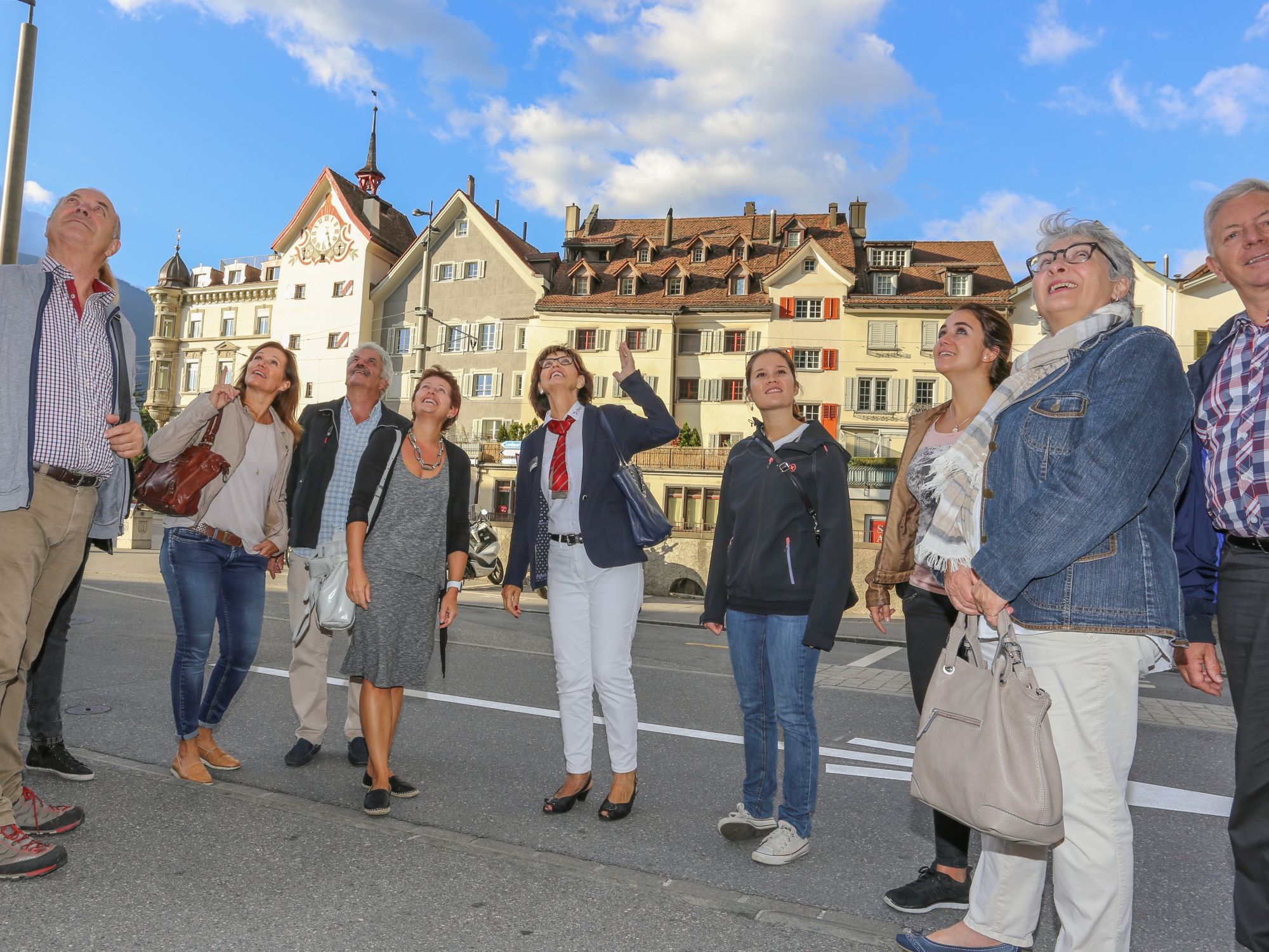 Guidad tur i Gamla stan i Chur med nyfikna deltagare under en blå himmel. Sevärdheter och historiska byggnader är synliga.