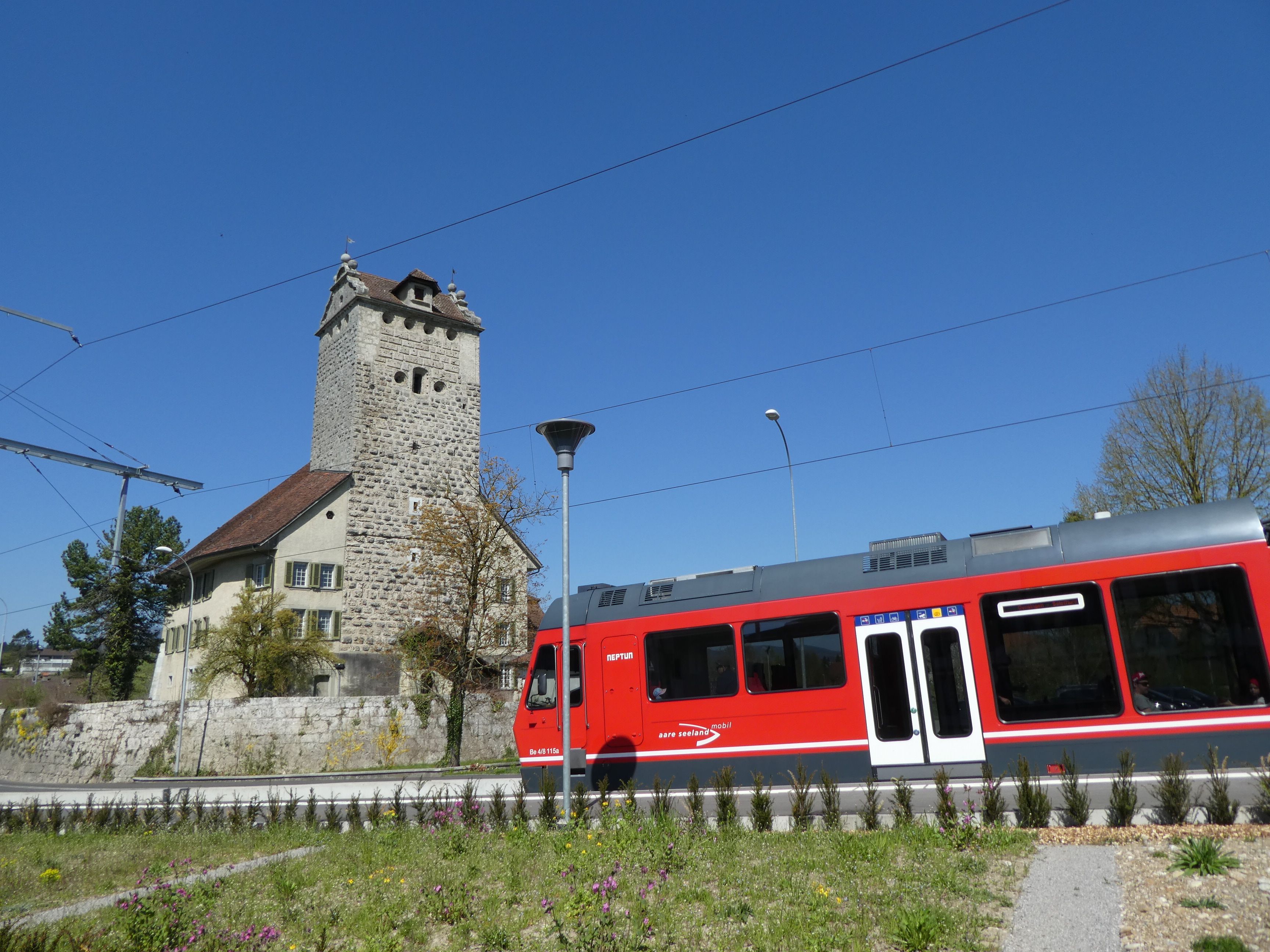 Sporvognen i Schweiz kører forbi den historiske station og blå himmel.